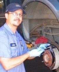 A man is working on the brake pads of a truck.