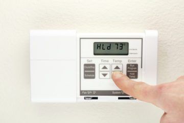 a person is pressing a button on a thermostat that is set to 73 degrees