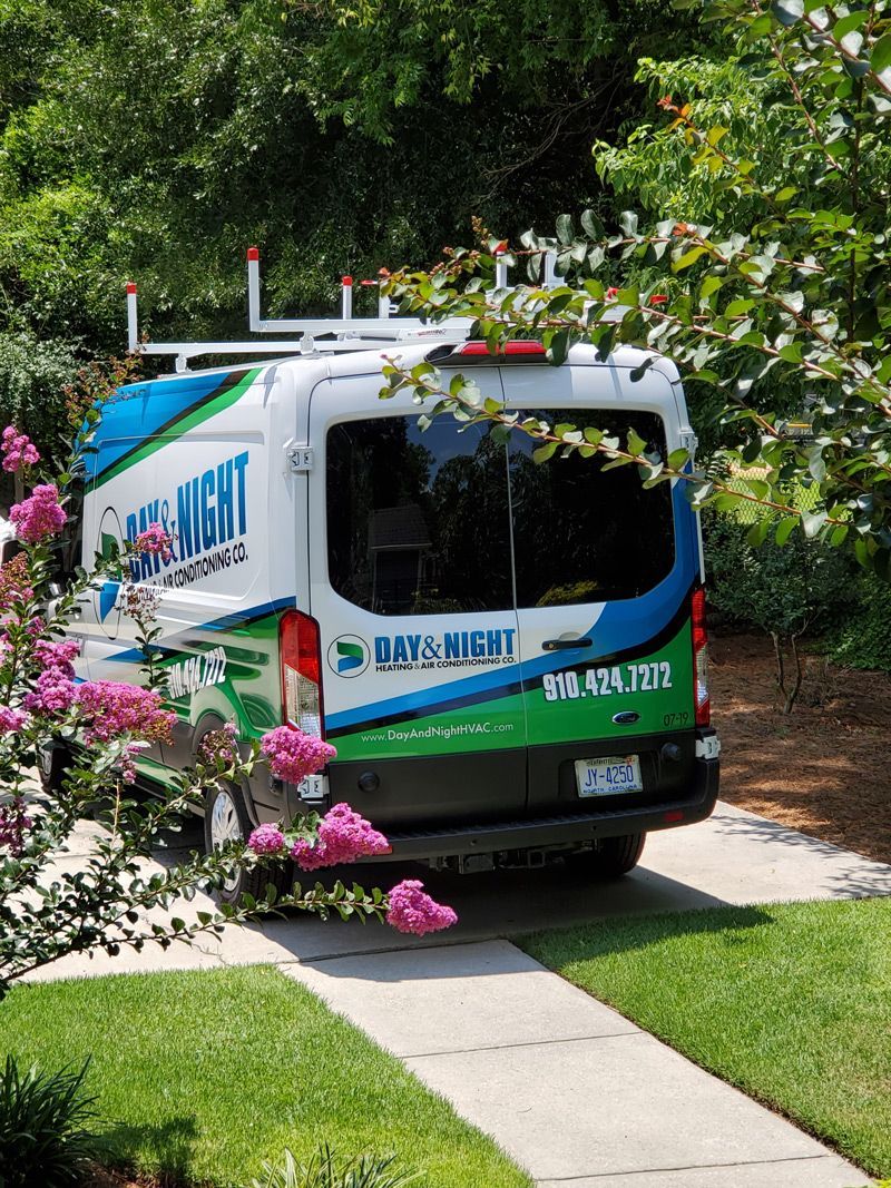 a blue and green van Day and Night Air Conditioning is parked in the driveway of a house