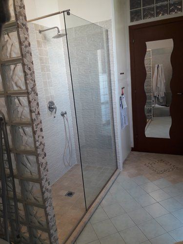 box doccia sulla sinistra con porta in legno e specchio
