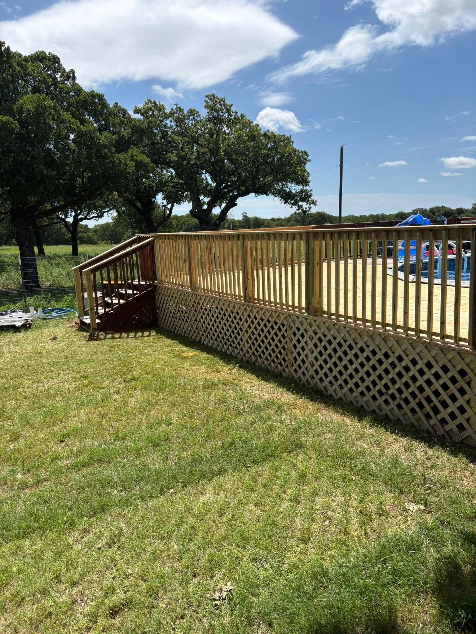 Two men are working on a wooden deck next to a pool.