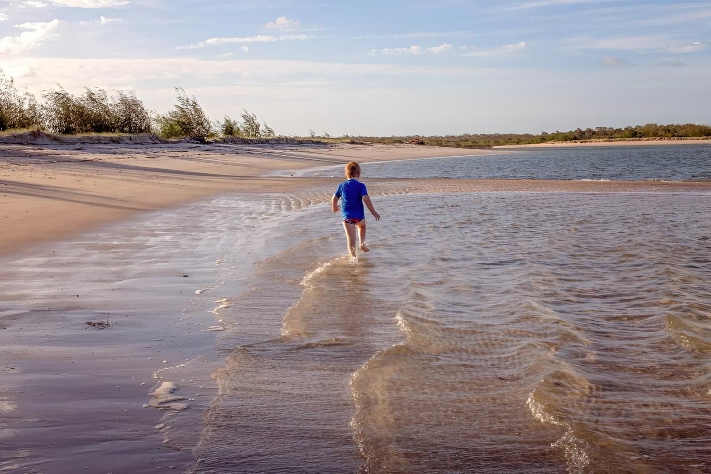 A Young Boy is Running in the Water on a Beach — Active Tree Fellas in Woodgate, QLD