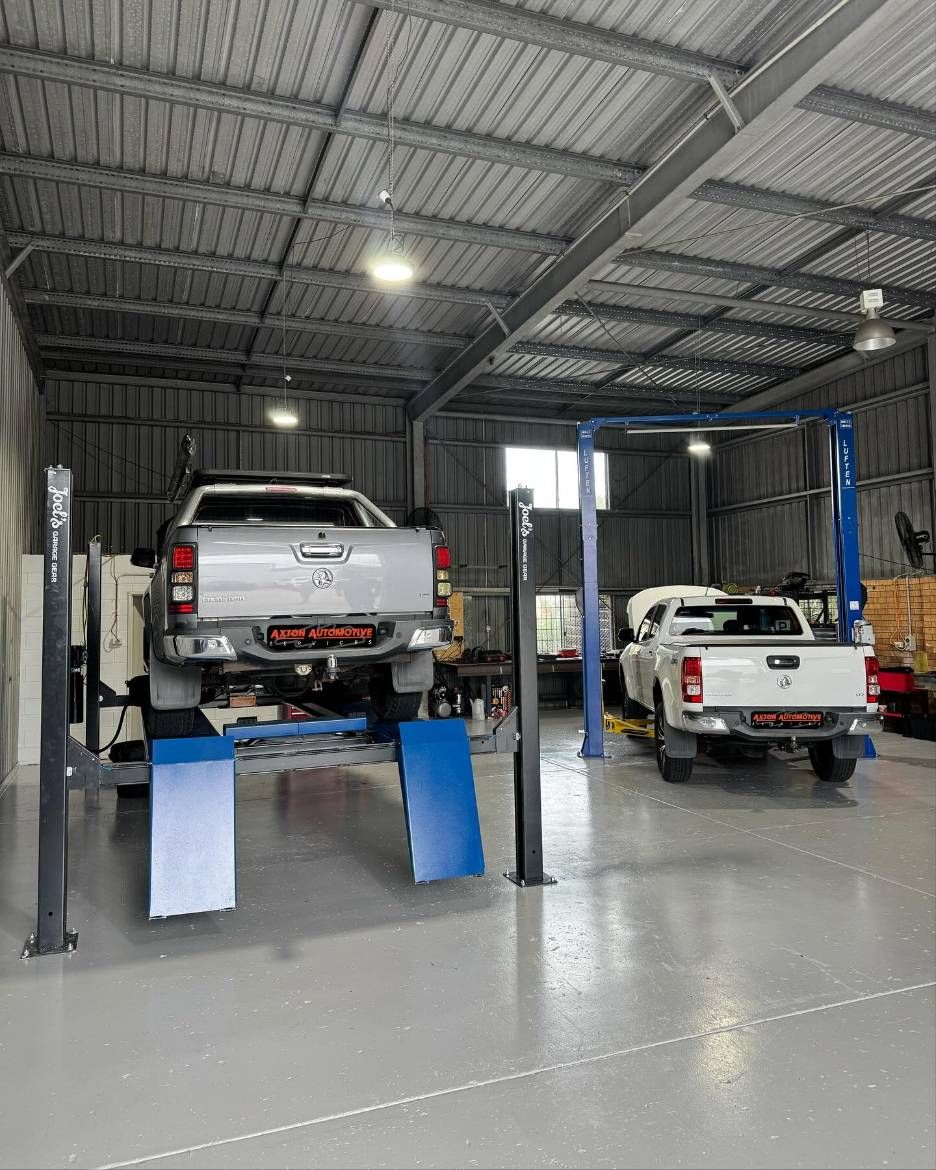 Two Trucks Are Sitting on a Lift in a Garage — Axton Automotive Services in Kunda Park, QLD