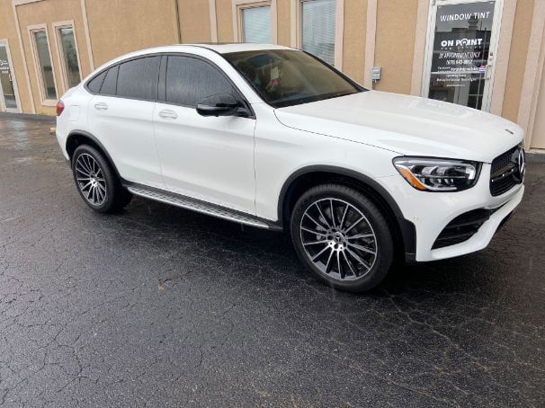 Red Dodge Challenger with black racing stripes parked in a garage.