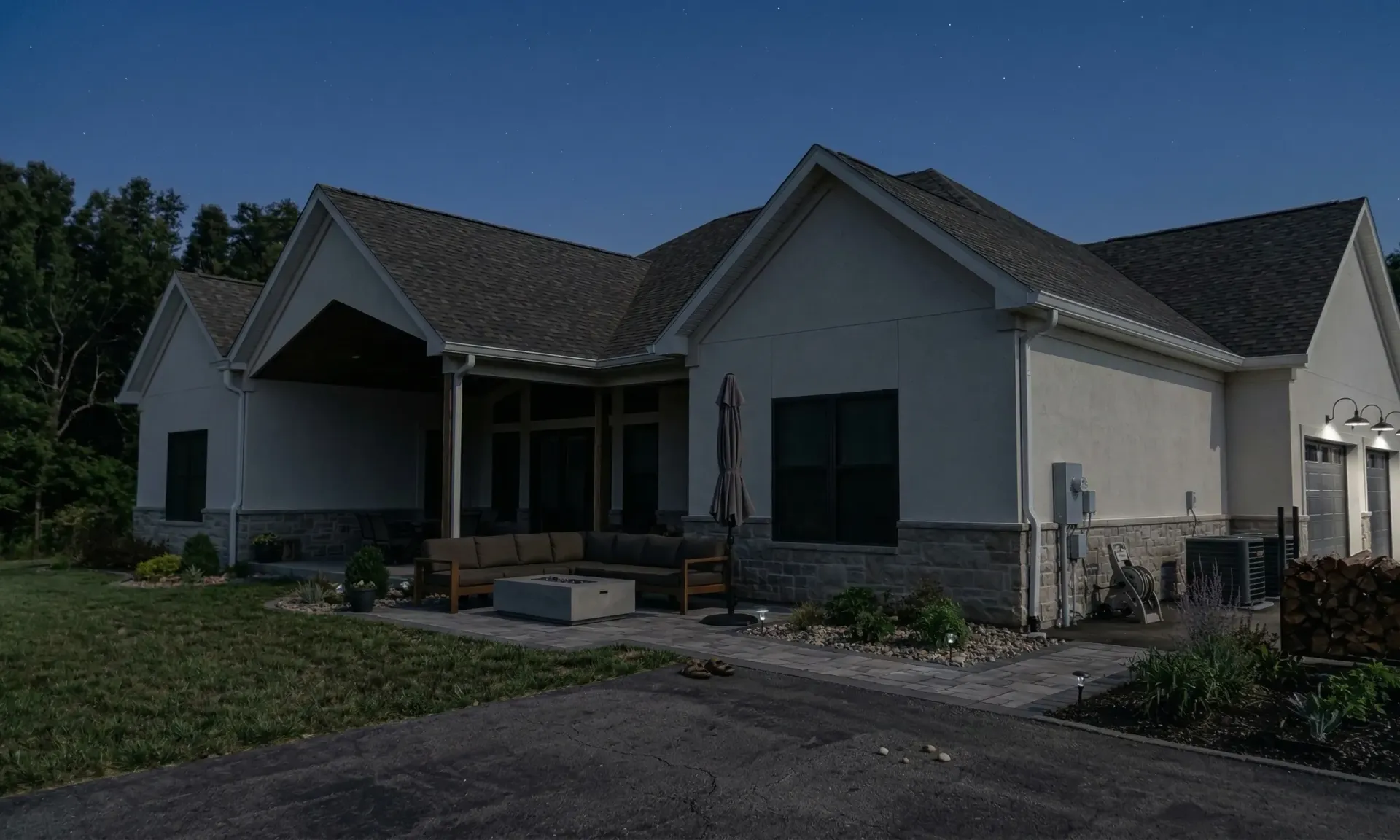 Brick house exterior with a black roof and white-framed windows, shrubbery, and a wall clock.