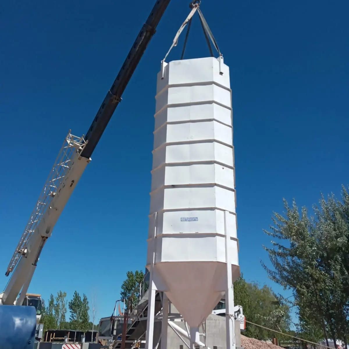 Un gran silo blanco está siendo levantado por una grúa.