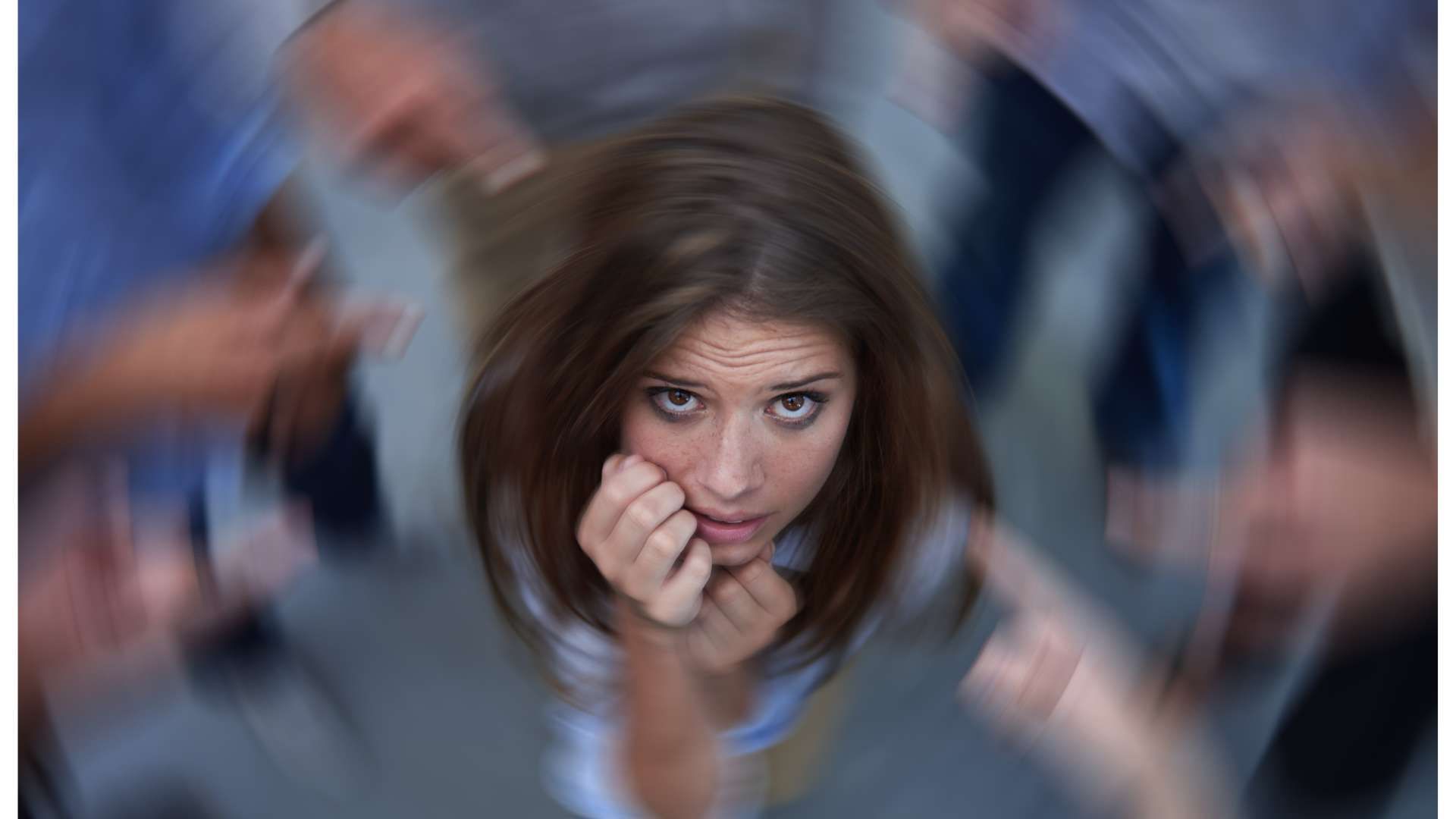 Blurred people in a crowd, with a worried woman centered and looking at the camera.