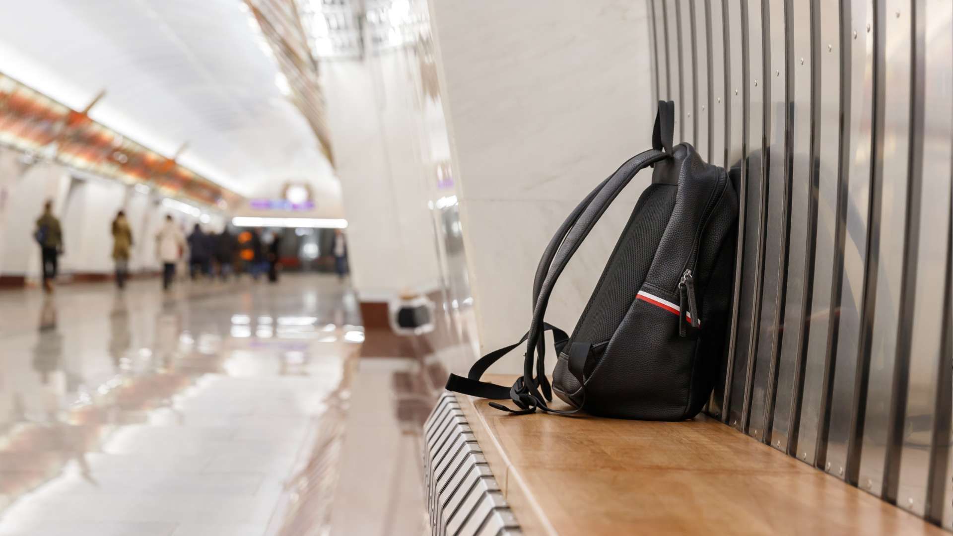 Black backpack on a bench in a bright airport terminal hallway
