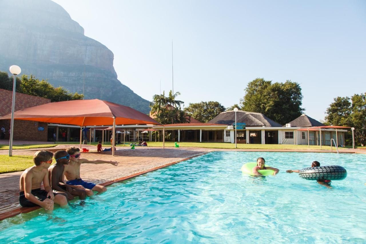 A group of people are sitting on the edge of a swimming pool.