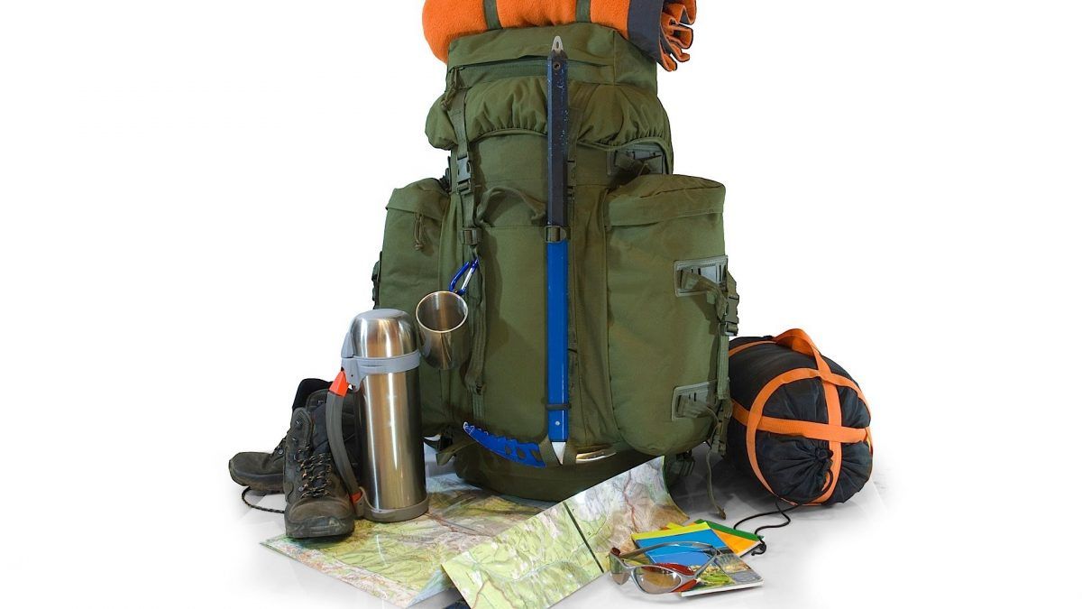 a person is standing next to a backpack filled with hiking gear .