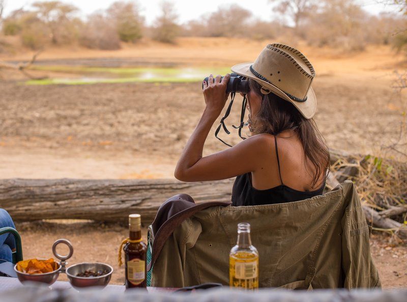 a woman in a safari hat is looking through binoculars