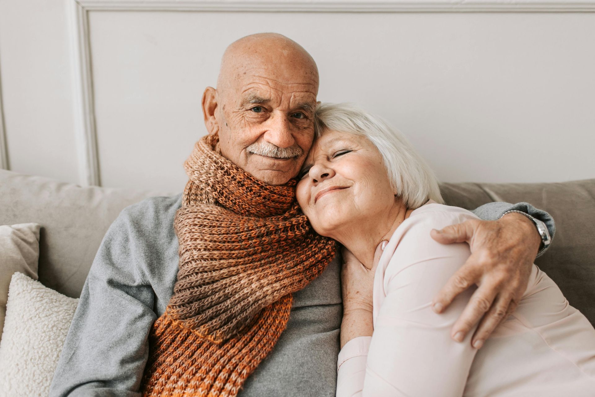 An elderly couple hugging each other on a rooftop at sunset.