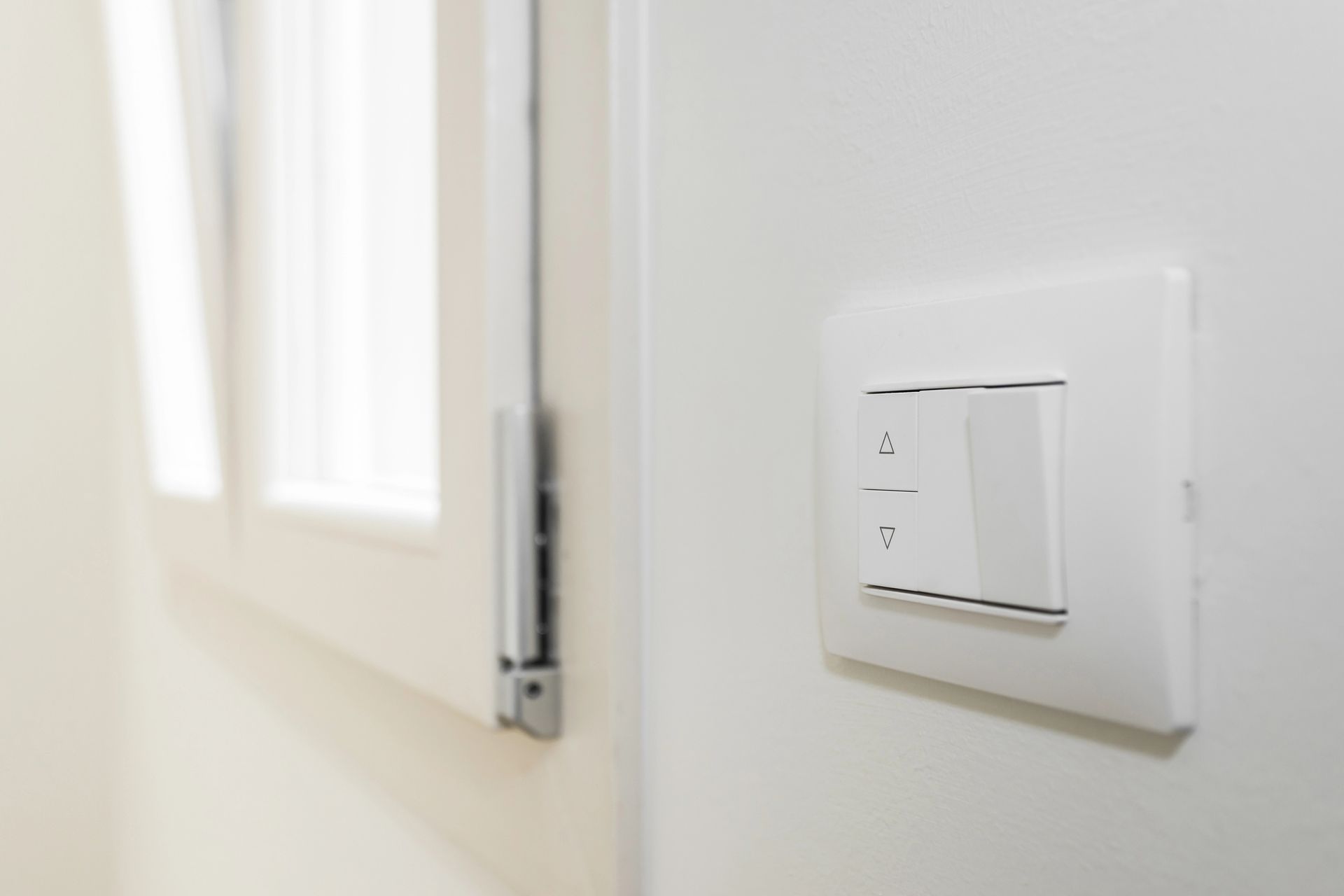 Interruttore della luce bianca su una parete bianca vicino a una finestra bianca.