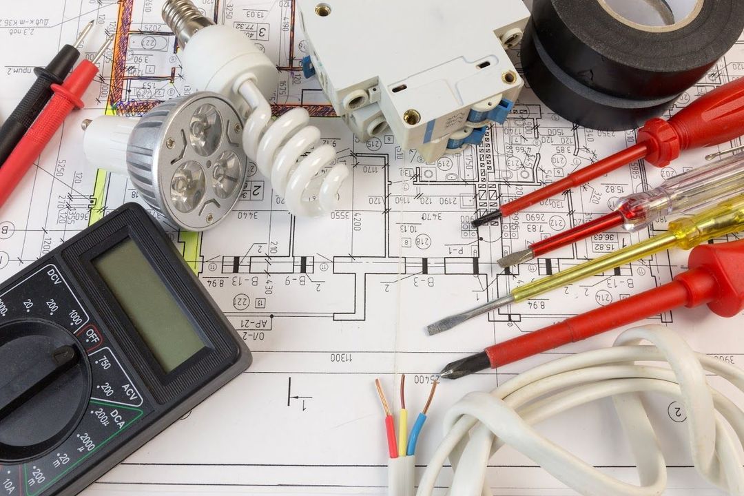 Utensili elettrici, lampadine e cavi sopra un progetto.