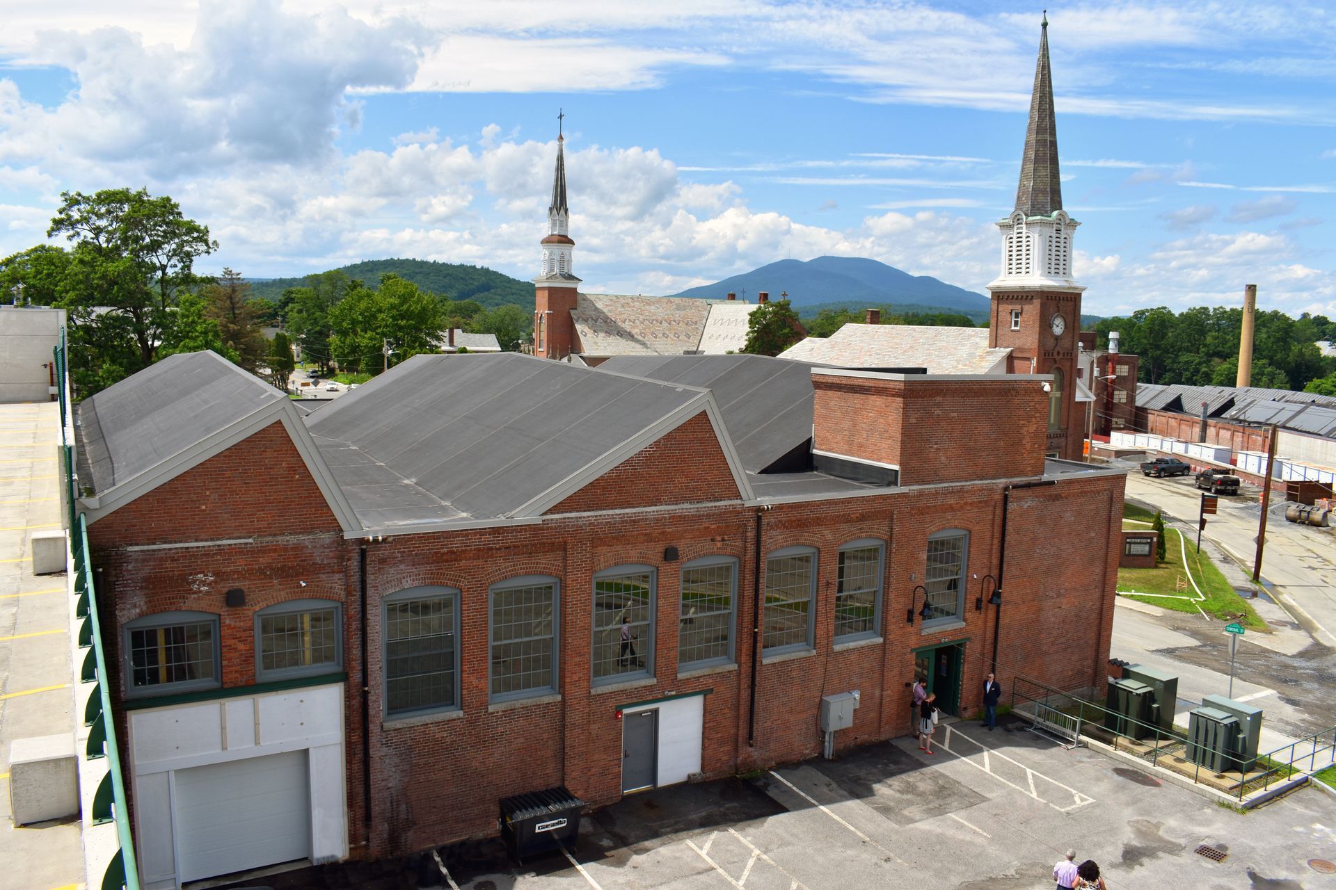 An aerial view of a brick building with a steeple in the background.