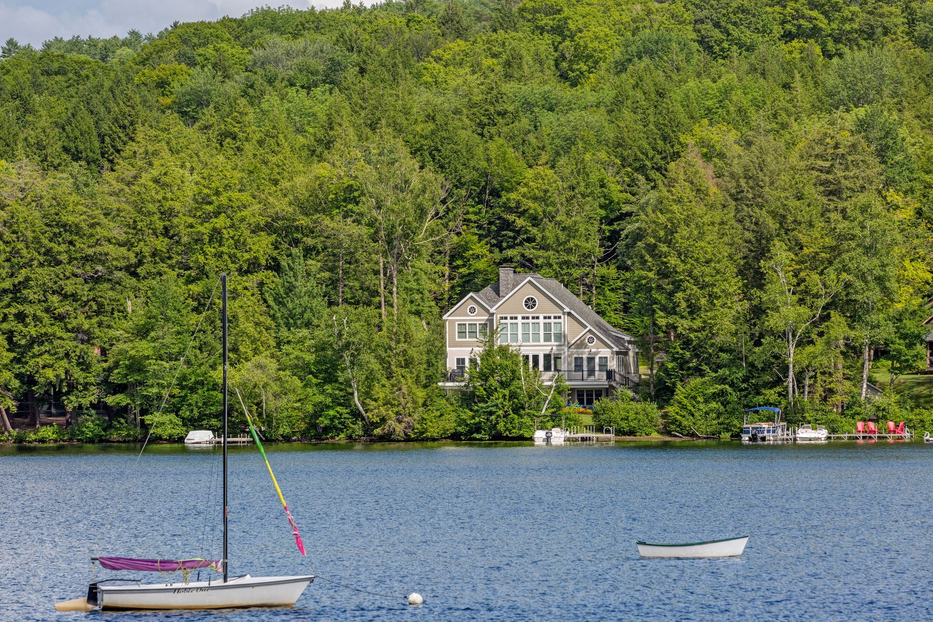 A boat is floating on a lake with a house in the background.