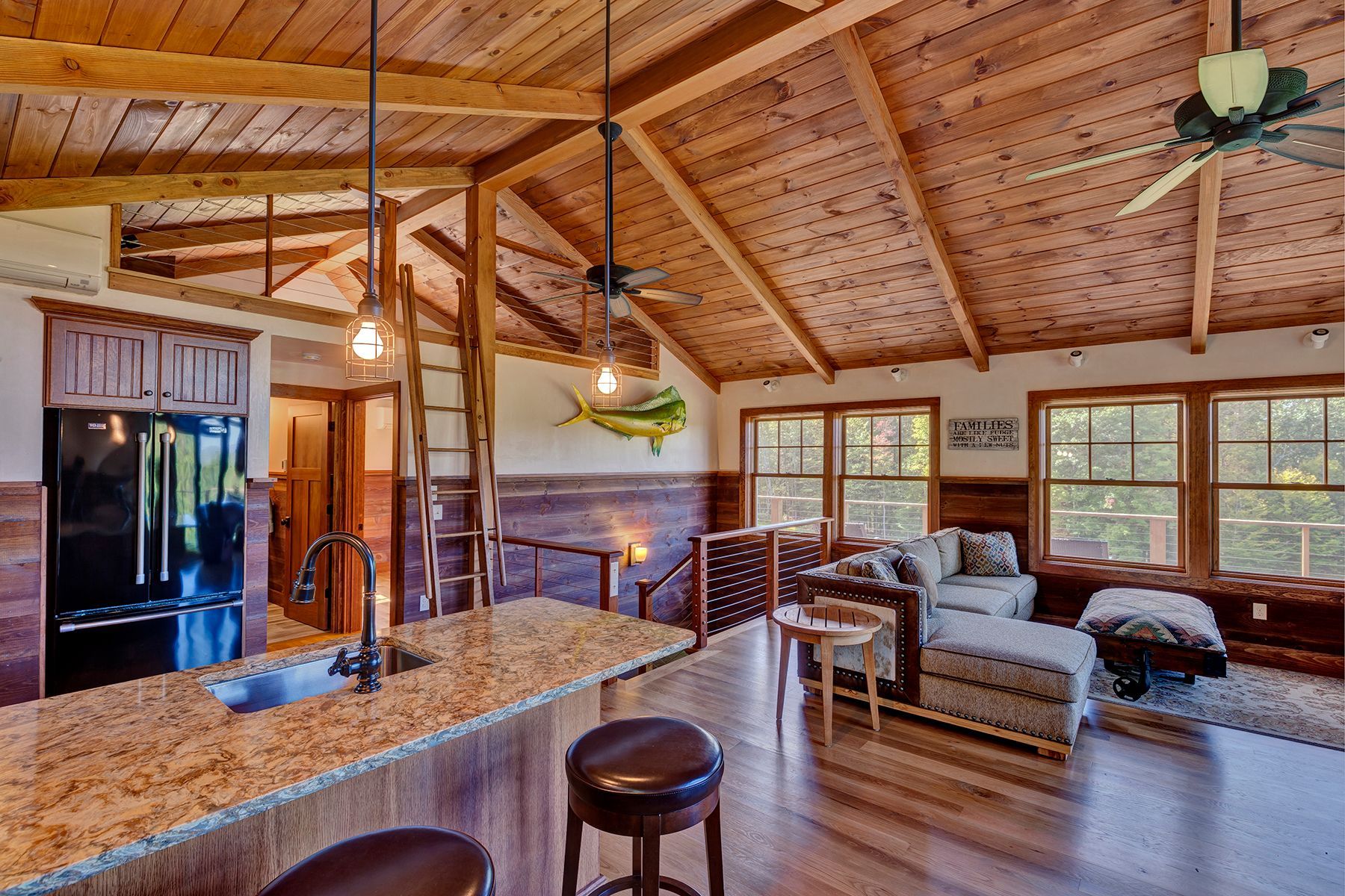 A kitchen and living room in a house with a ceiling fan.