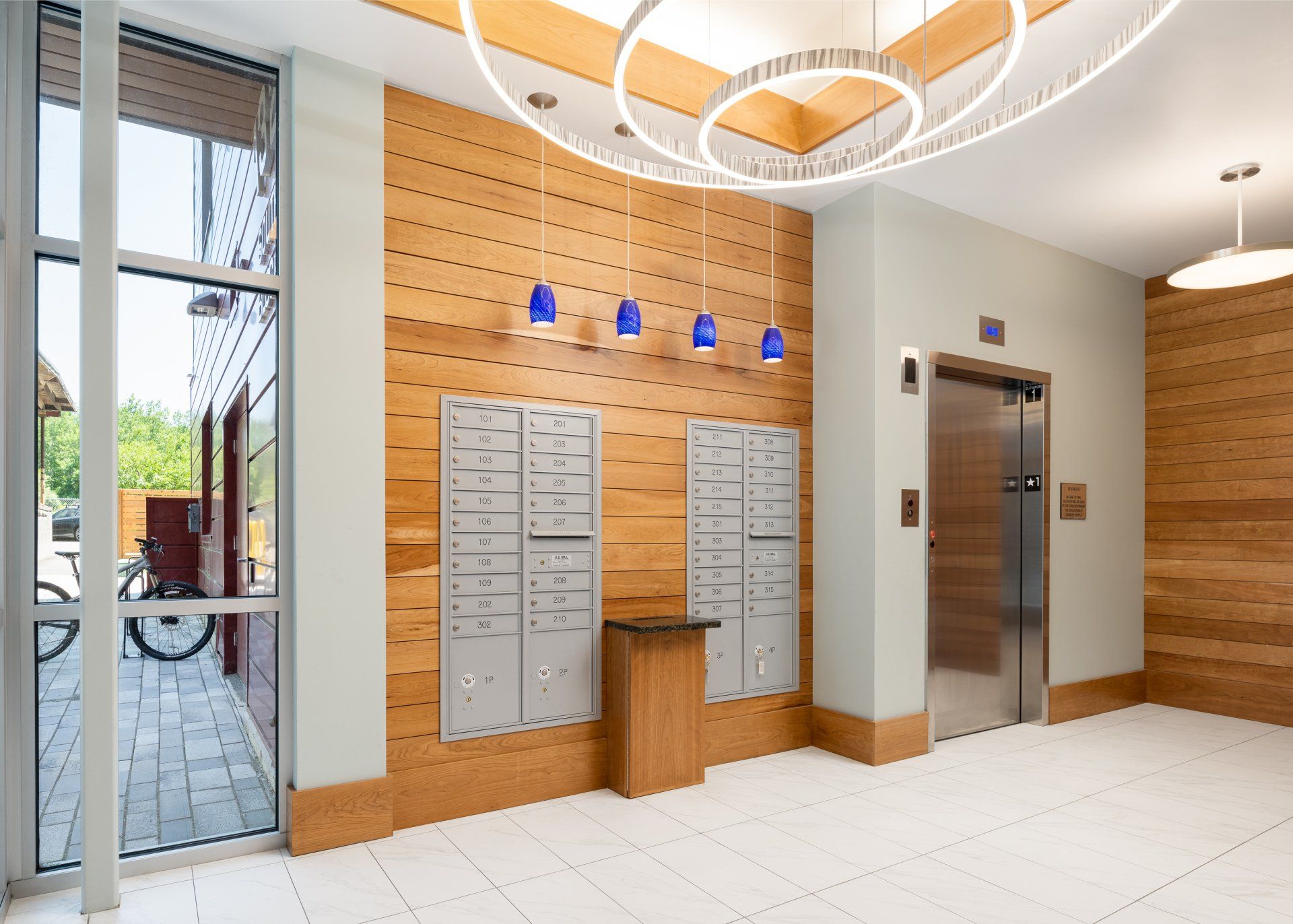 A large lobby with a stainless steel elevator and wooden walls.