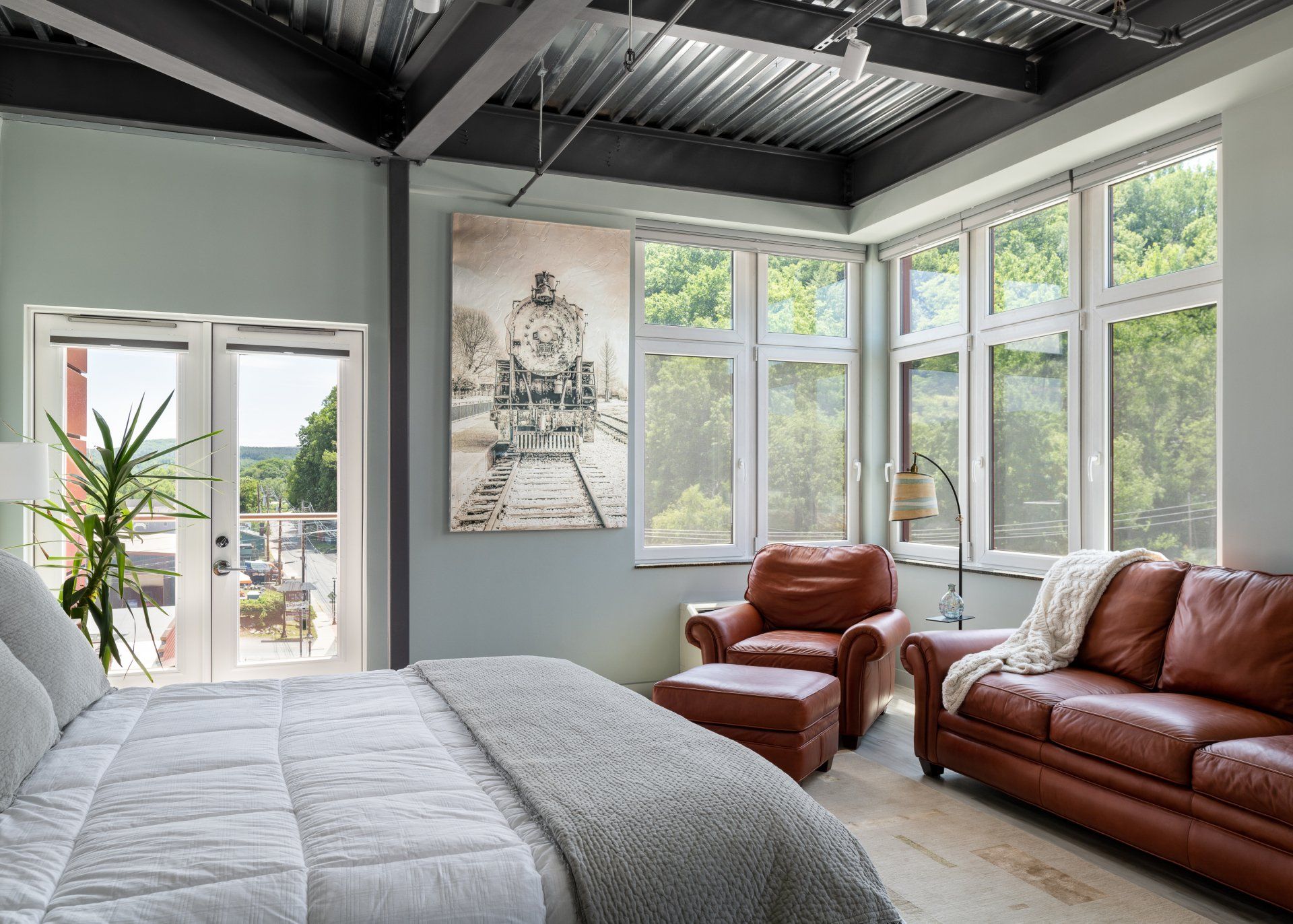 A bedroom with a bed , couch , chair and painting on the wall.