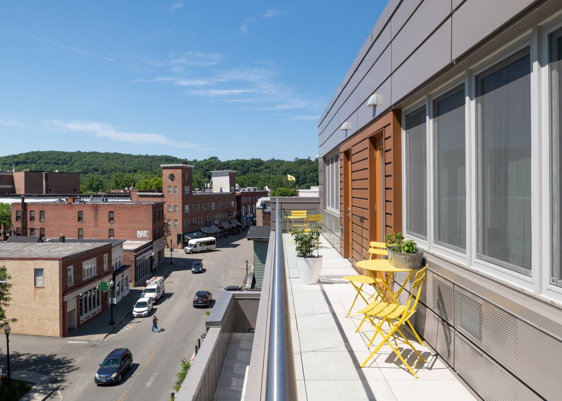 A balcony with a table and chairs on it overlooking a city street.