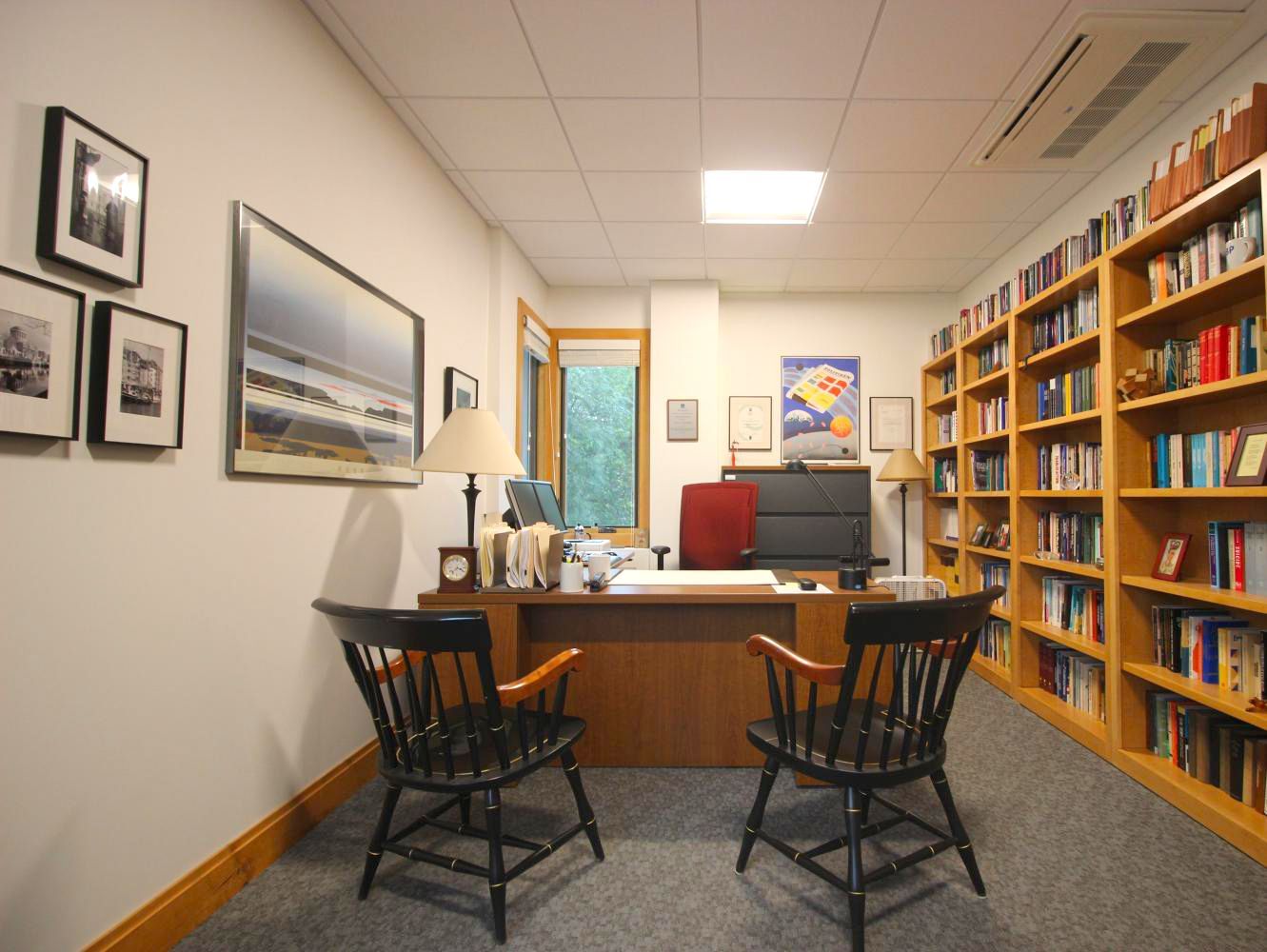 A room with a desk and two chairs in it