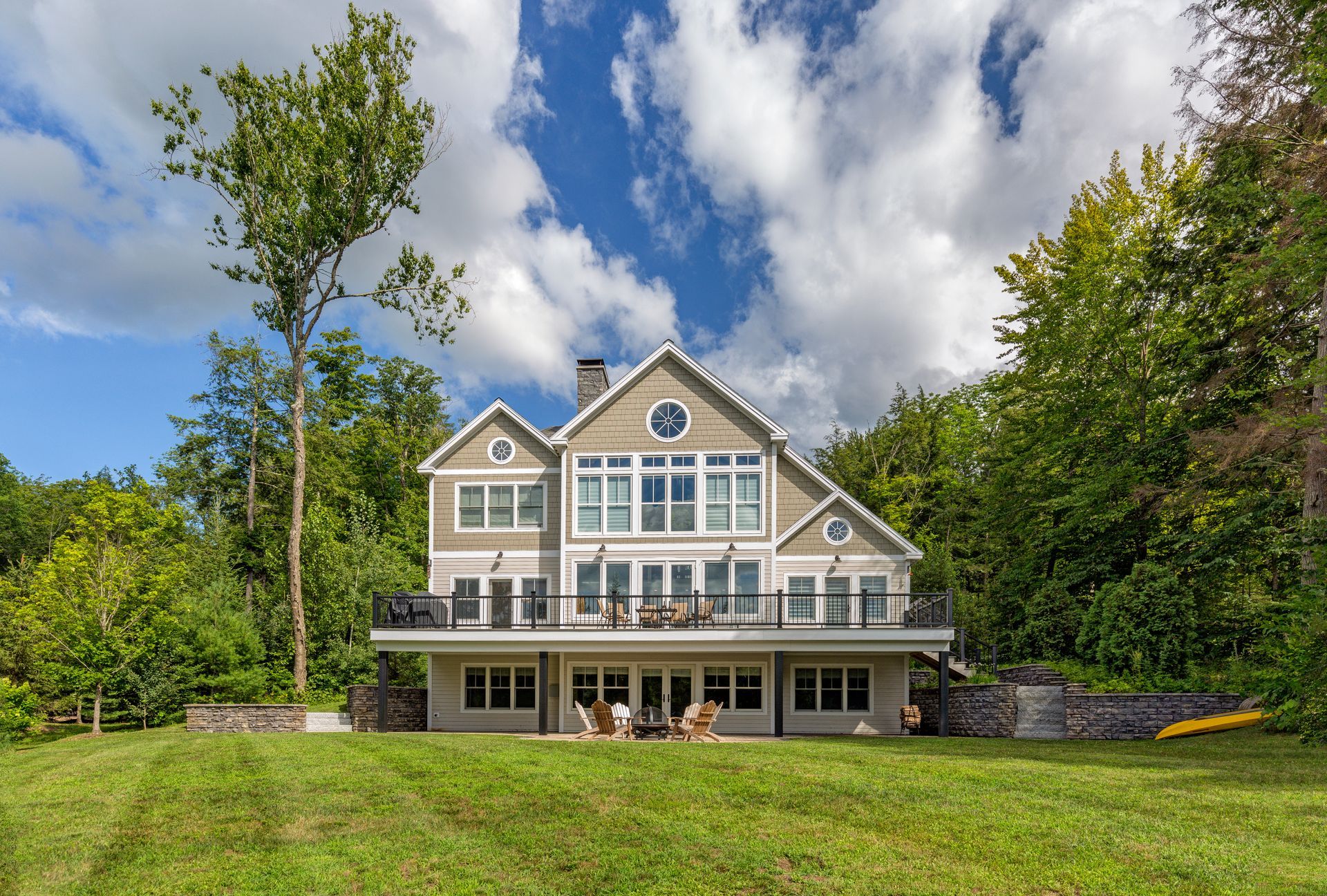 A large house is sitting on top of a lush green hillside surrounded by trees.