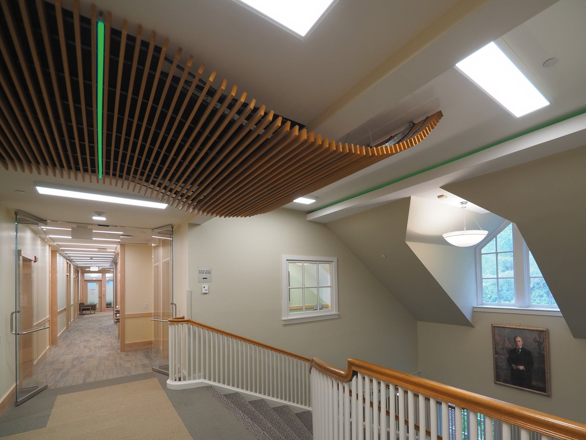 A hallway with a railing and a painting on the wall