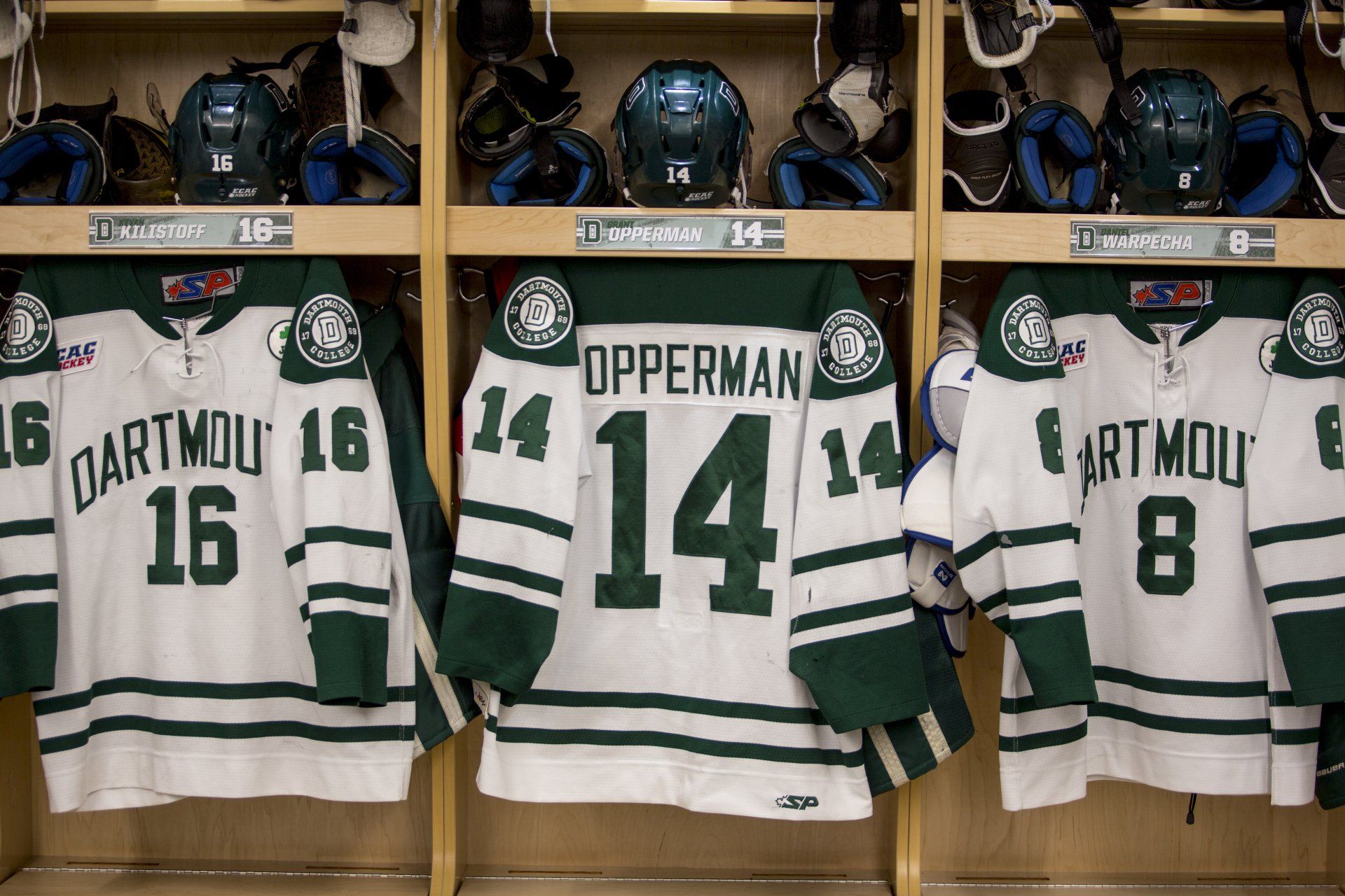 A row of hockey jerseys hanging in a locker room.