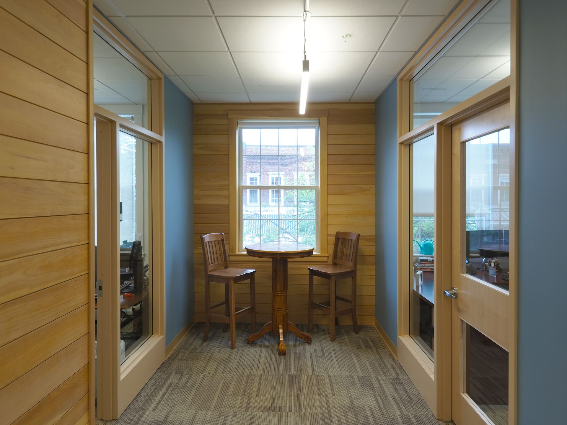 A hallway with a table and chairs in front of a window