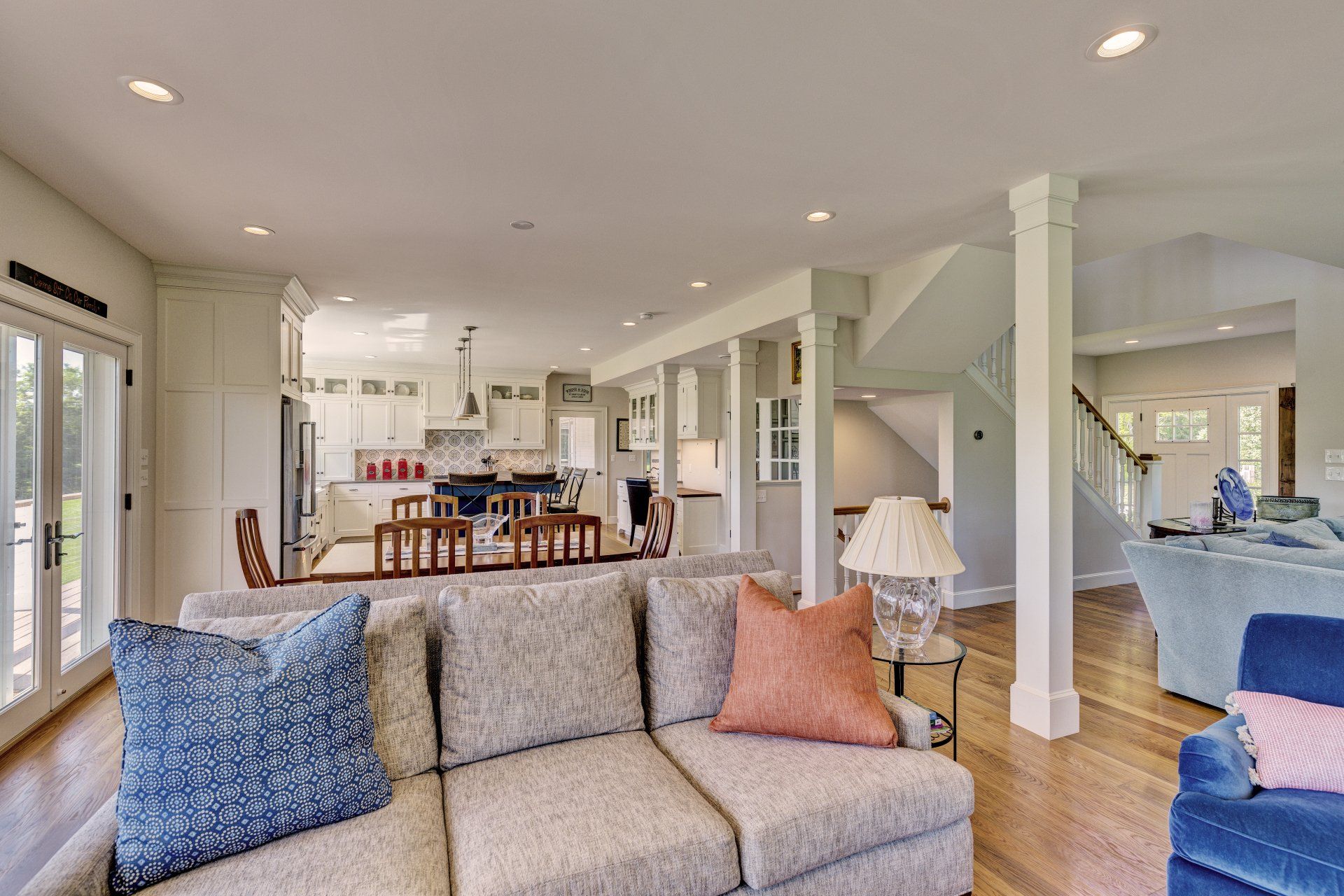 A living room with a couch and chairs and a kitchen in the background