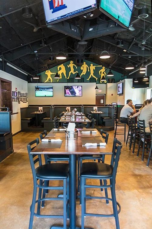 A restaurant with tables and chairs and televisions on the ceiling.