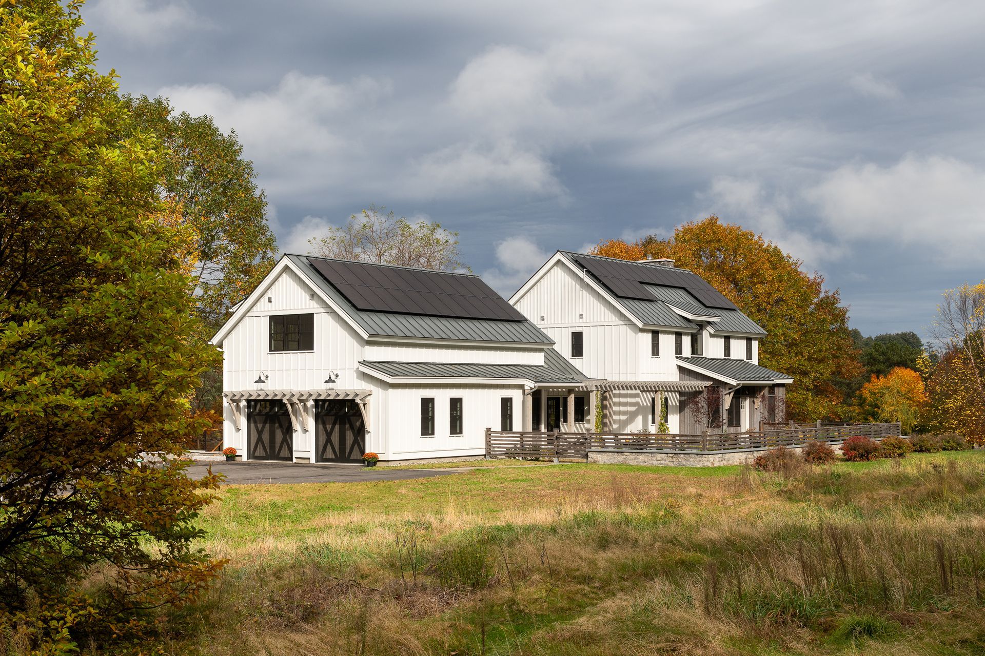 A white house with solar panels on the roof is sitting in the middle of a field.