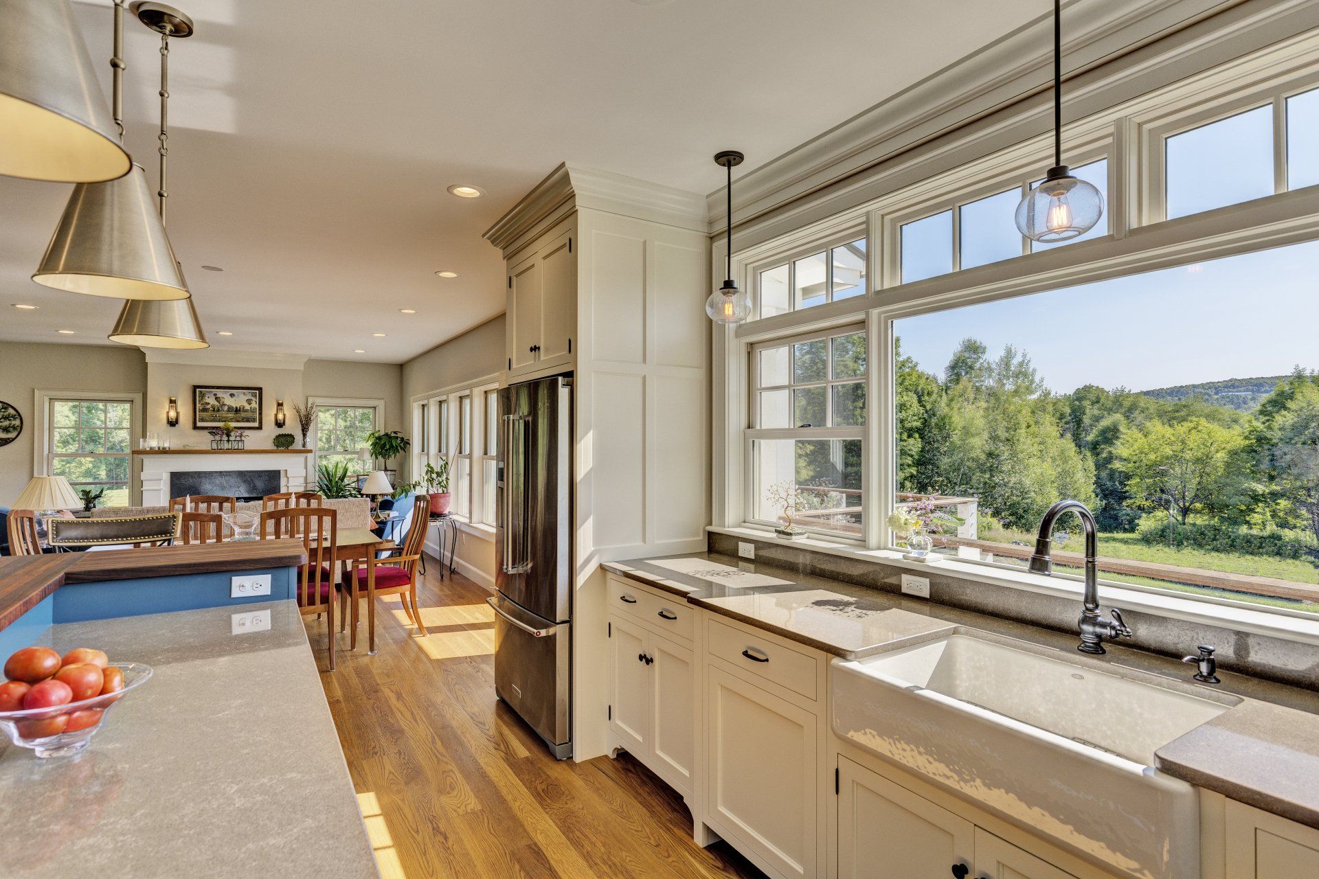 A kitchen with a sink , refrigerator , and large window.