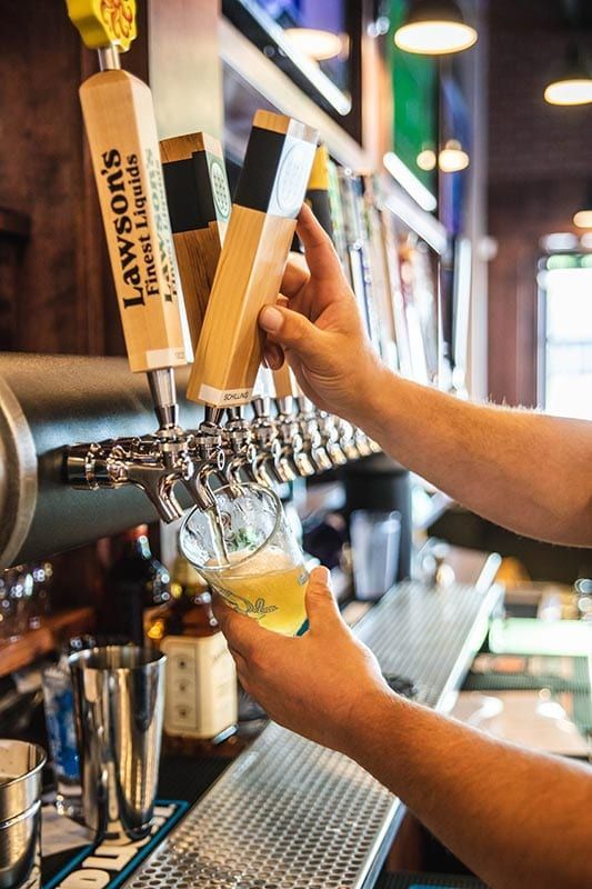 A person is pouring beer from a tap at a bar.