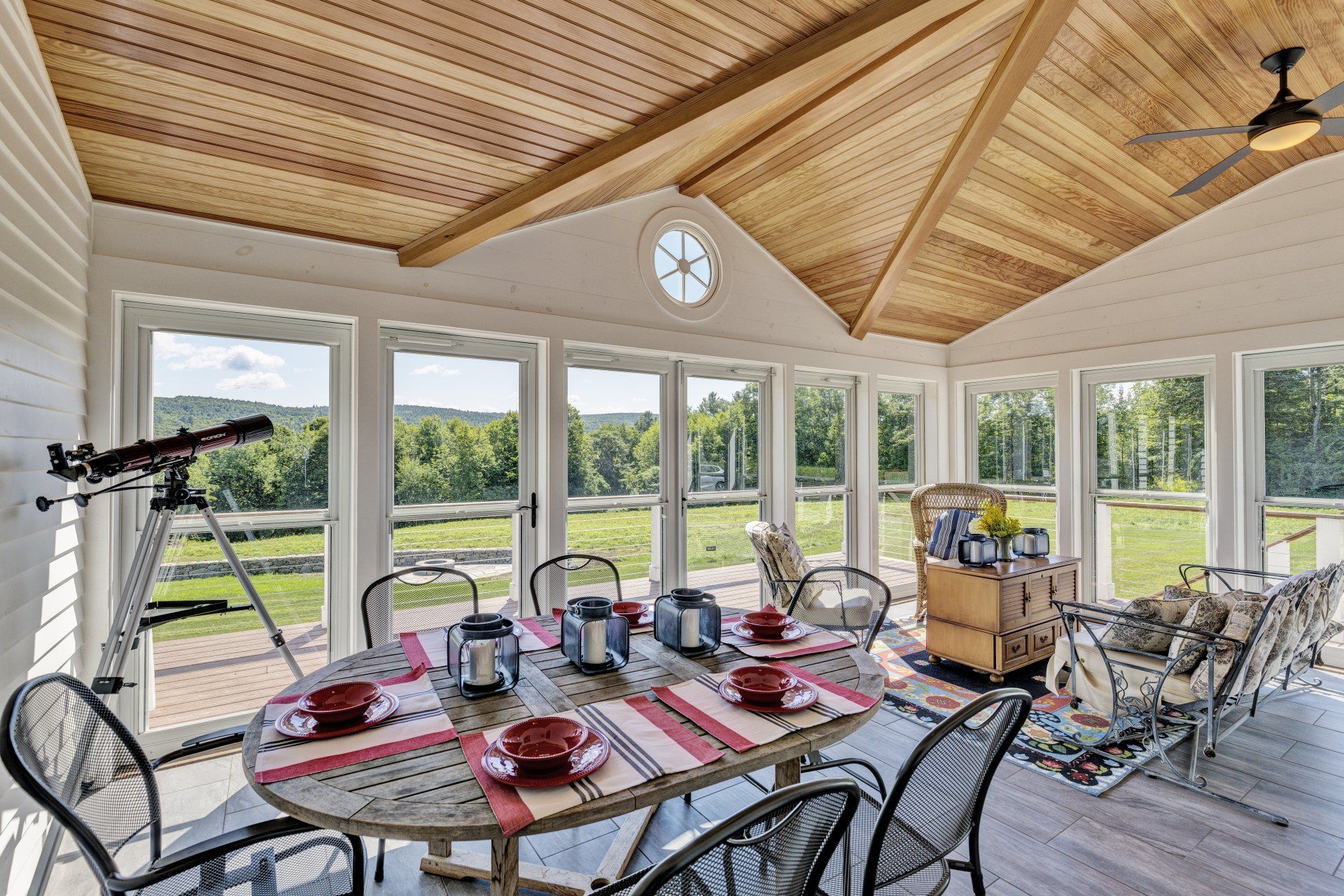 A sun room with a table and chairs and a telescope.