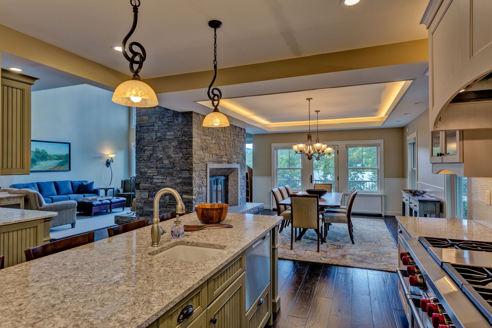 A kitchen with granite counter tops , a stove , a sink , and a fireplace.