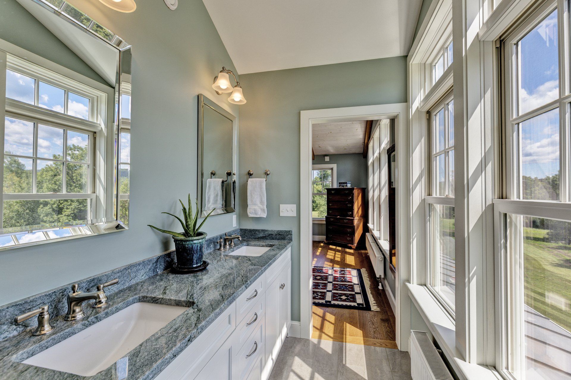 A bathroom with two sinks , a mirror , and lots of windows.