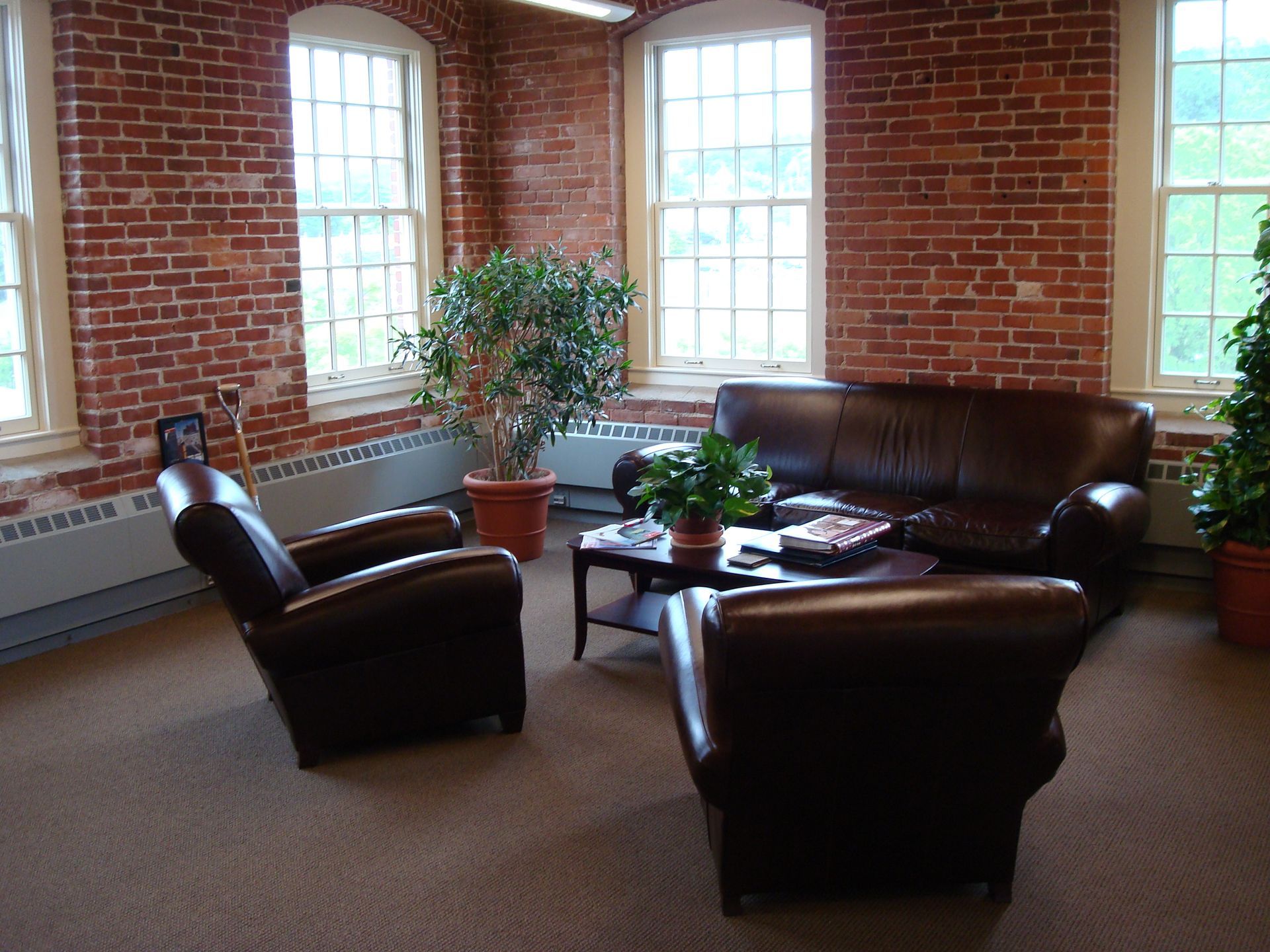 A living room with a couch and chairs in front of a brick wall