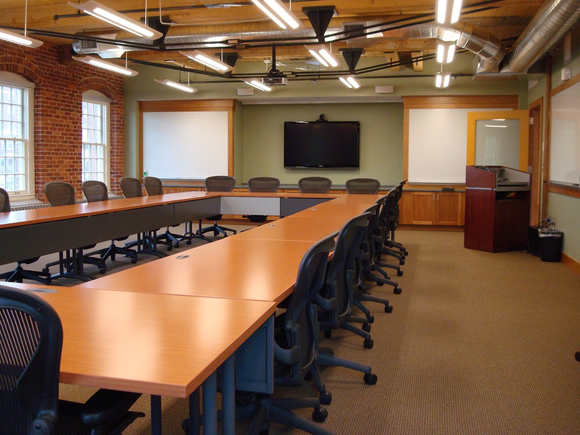A conference room with tables and chairs and a flat screen tv on the wall