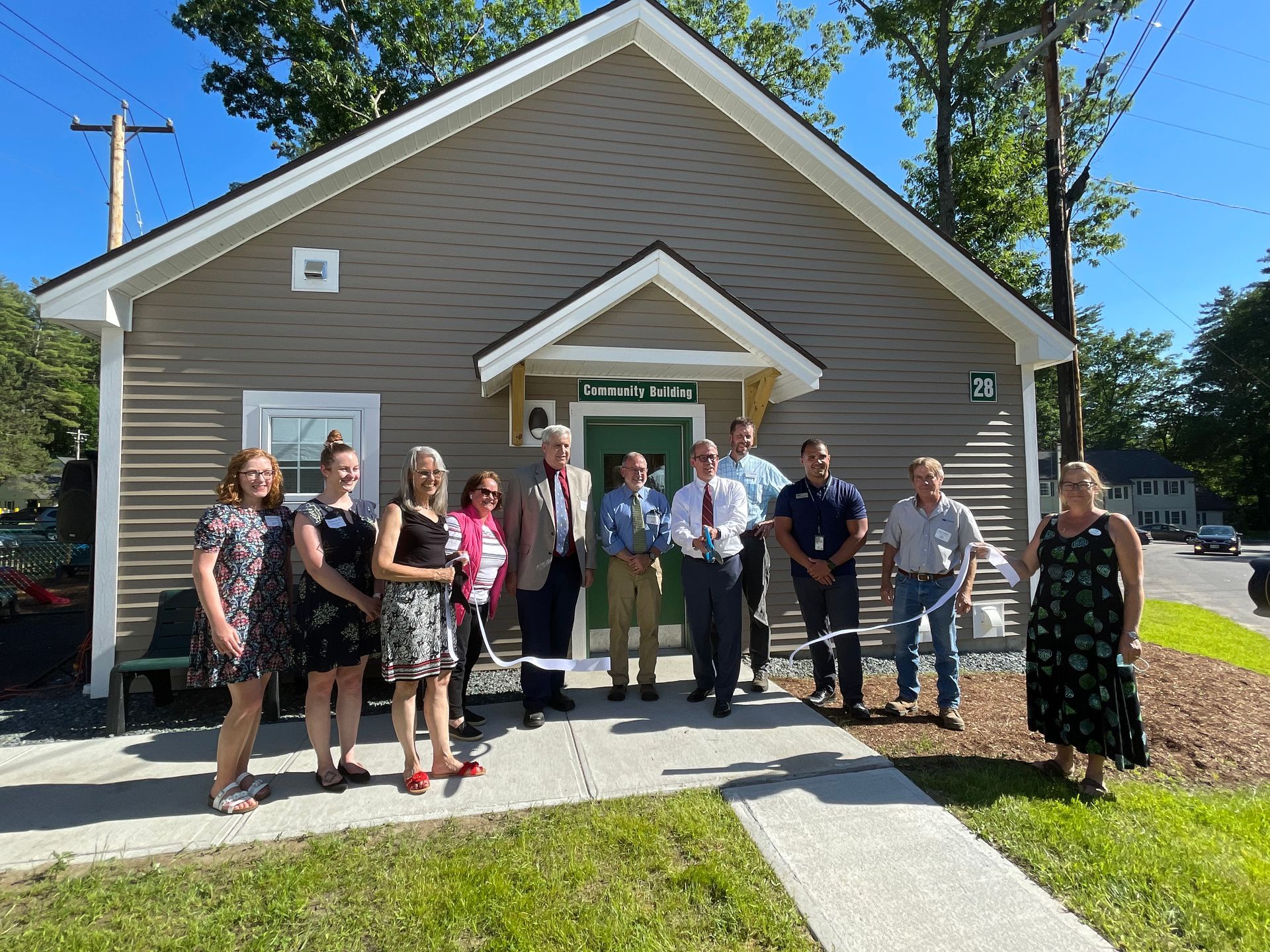 A group of people are standing in front of a small house.