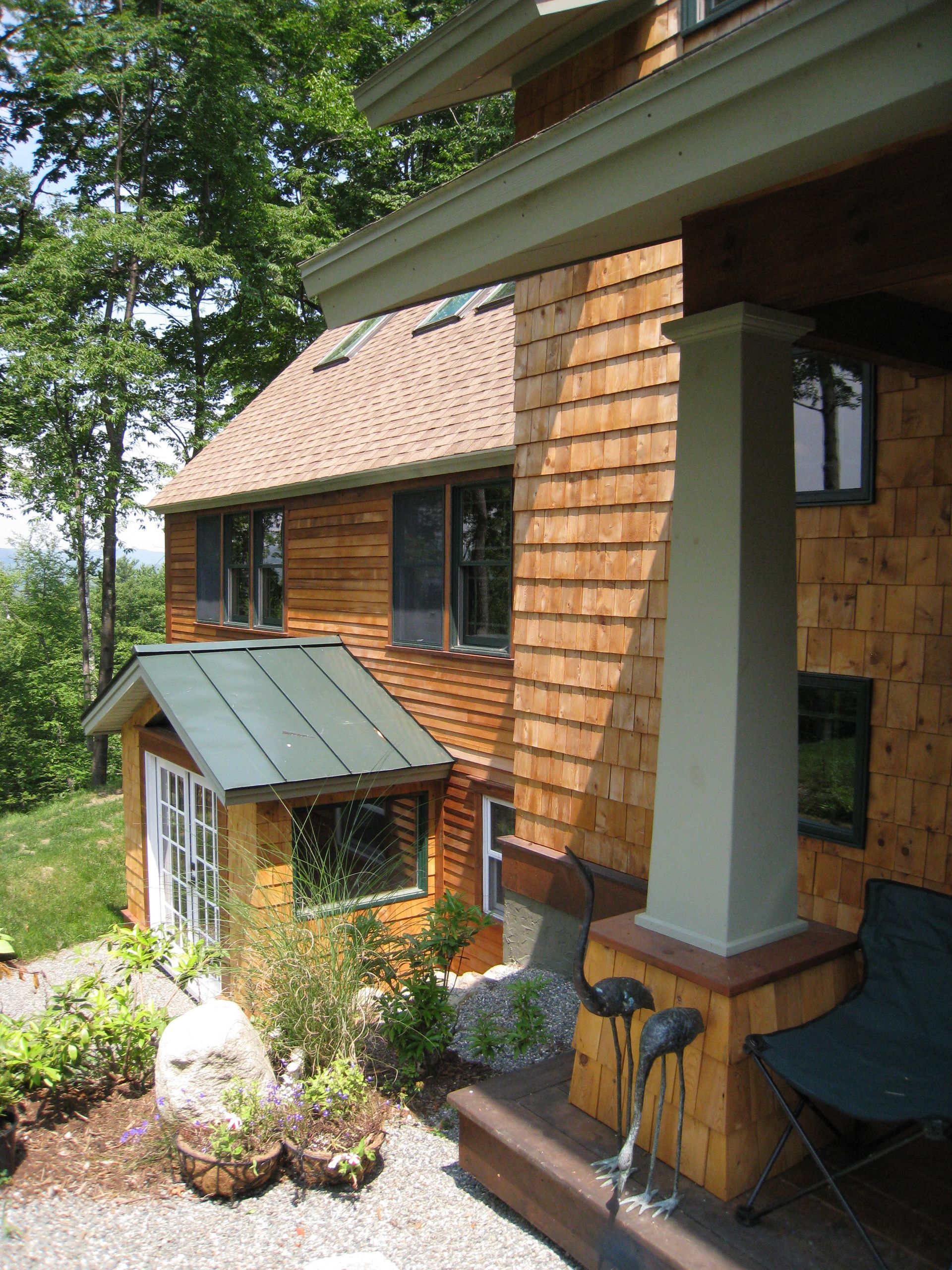 A house with a green roof sits on a hillside