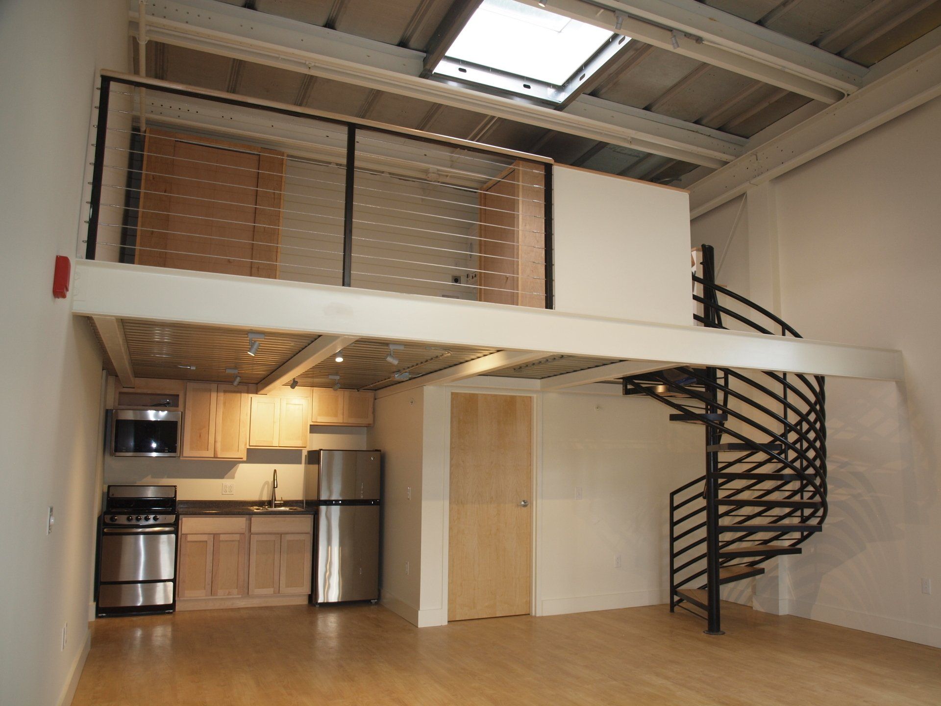 An empty kitchen with a spiral staircase leading to the second floor