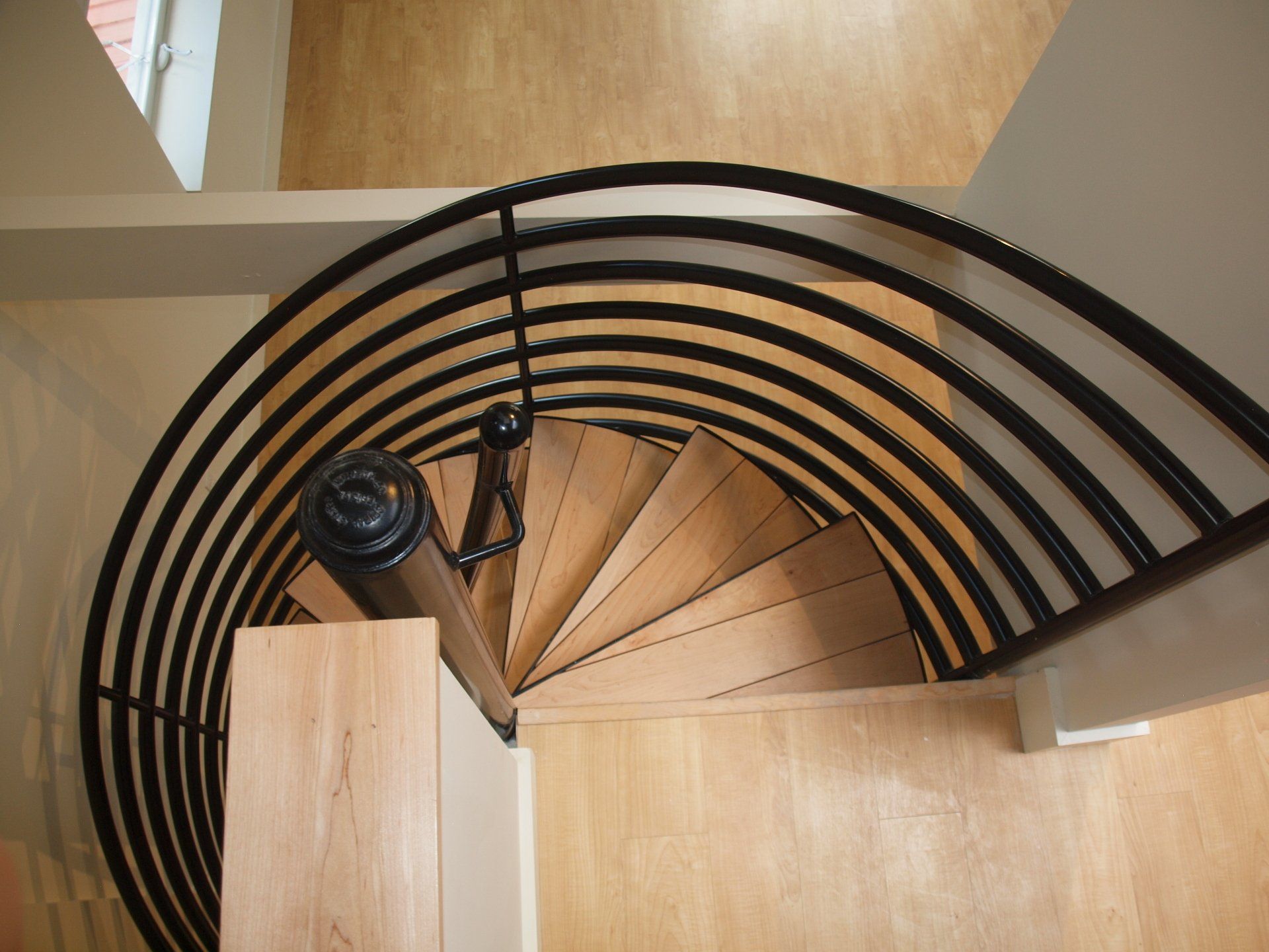 A spiral staircase with a black railing and wooden steps