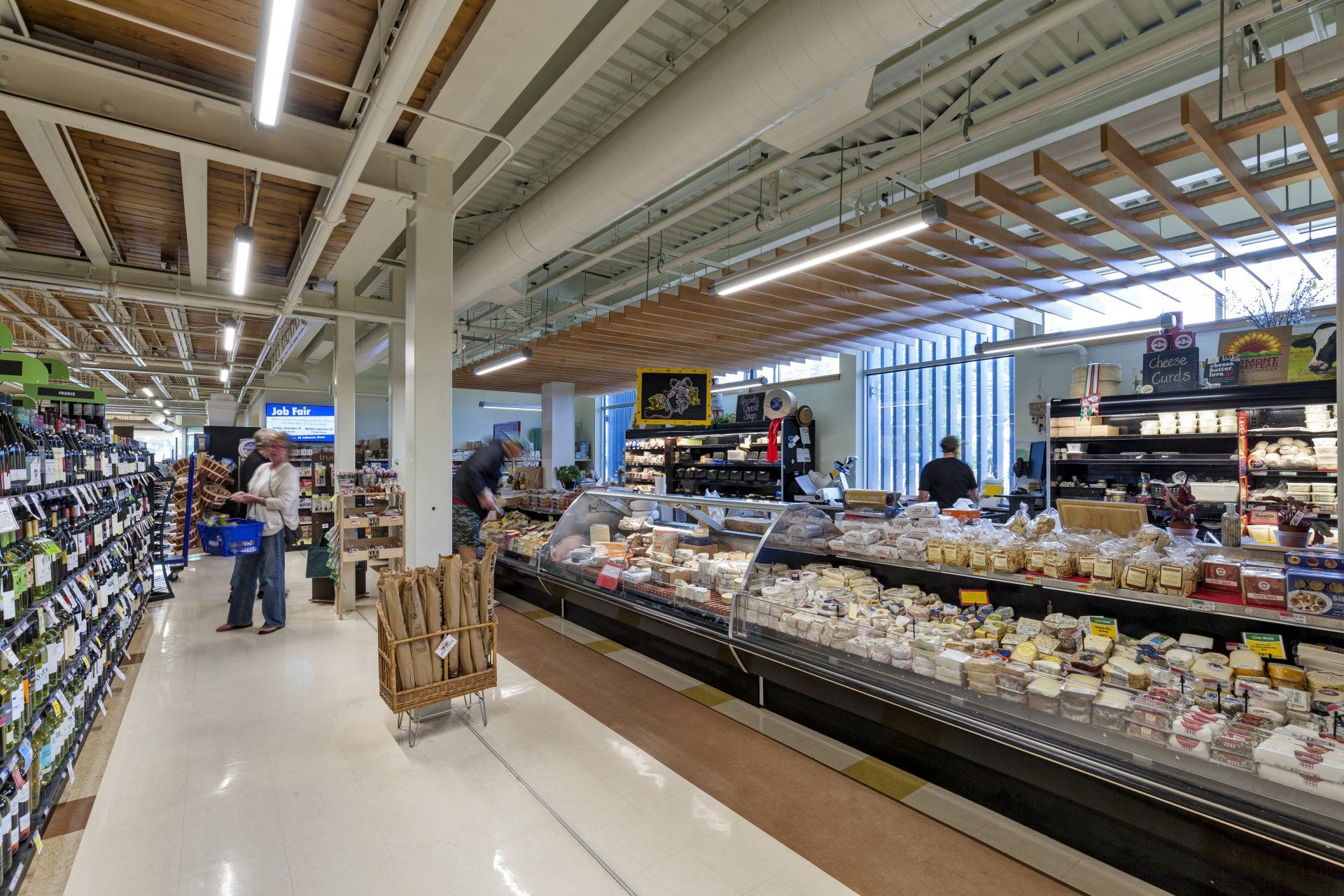 A grocery store aisle filled with lots of food and people shopping.