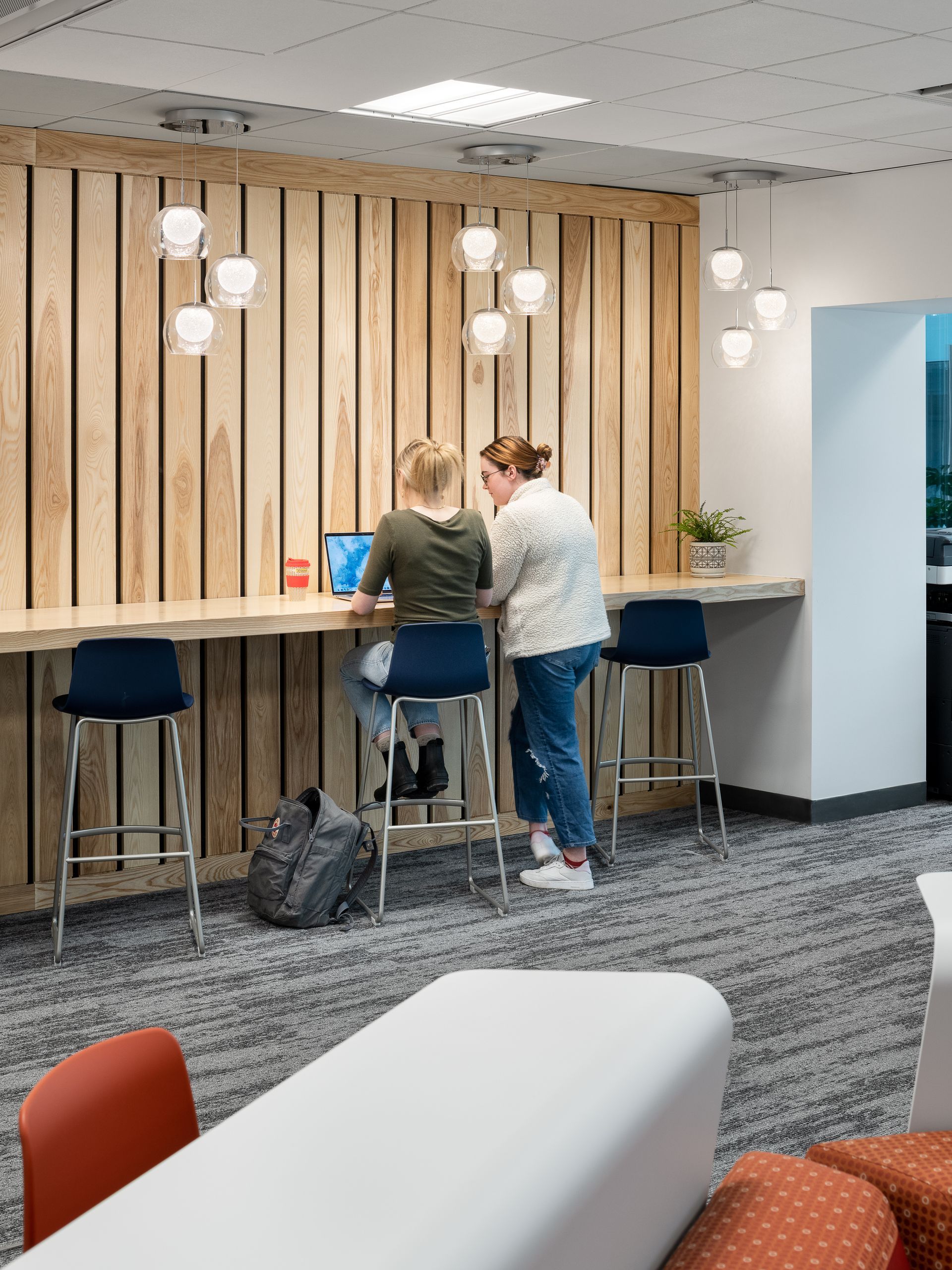 Two women are sitting at a table with a laptop.