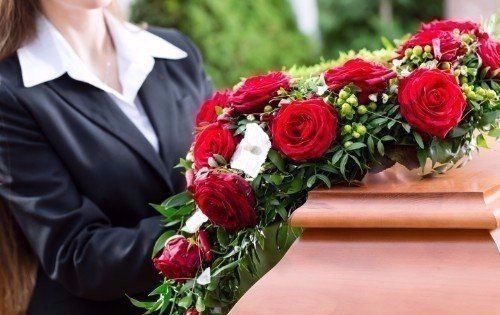 Donna mettendo di fiori rossi sulla bara