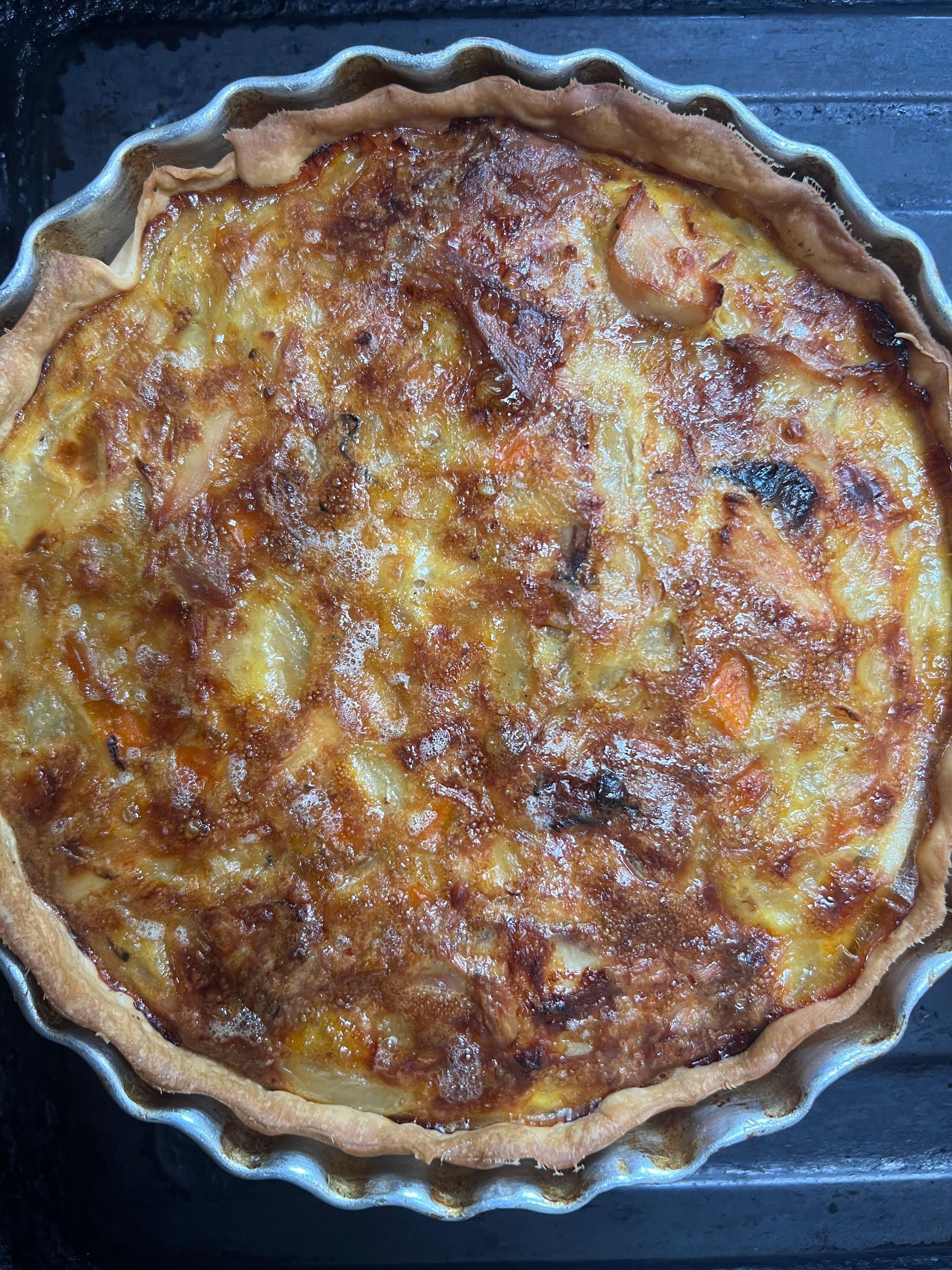 Un primer plano de una quiche en una sartén sobre una mesa.