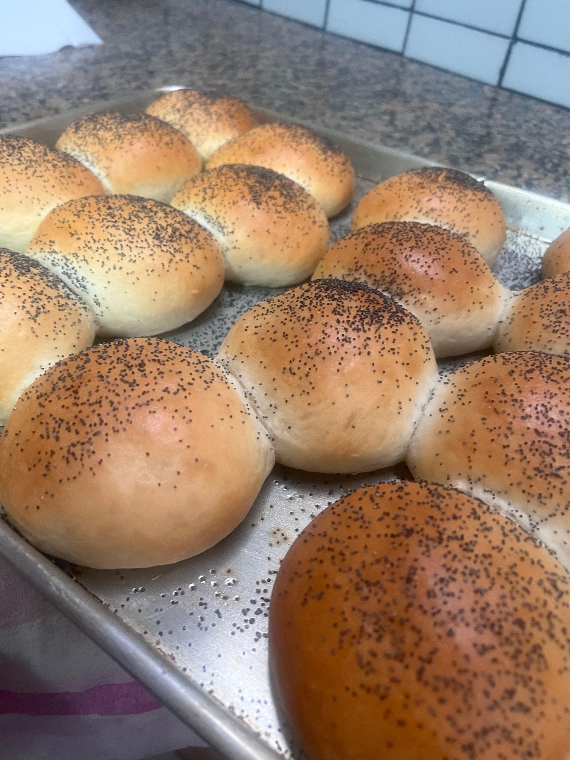 Una bandeja de bollos con semillas de amapola encima.