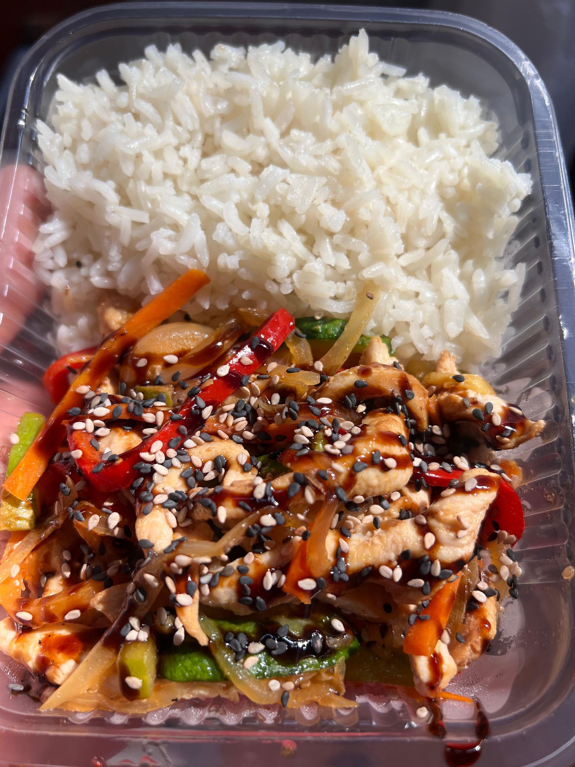 Un recipiente de plástico lleno de arroz, pollo y verduras.