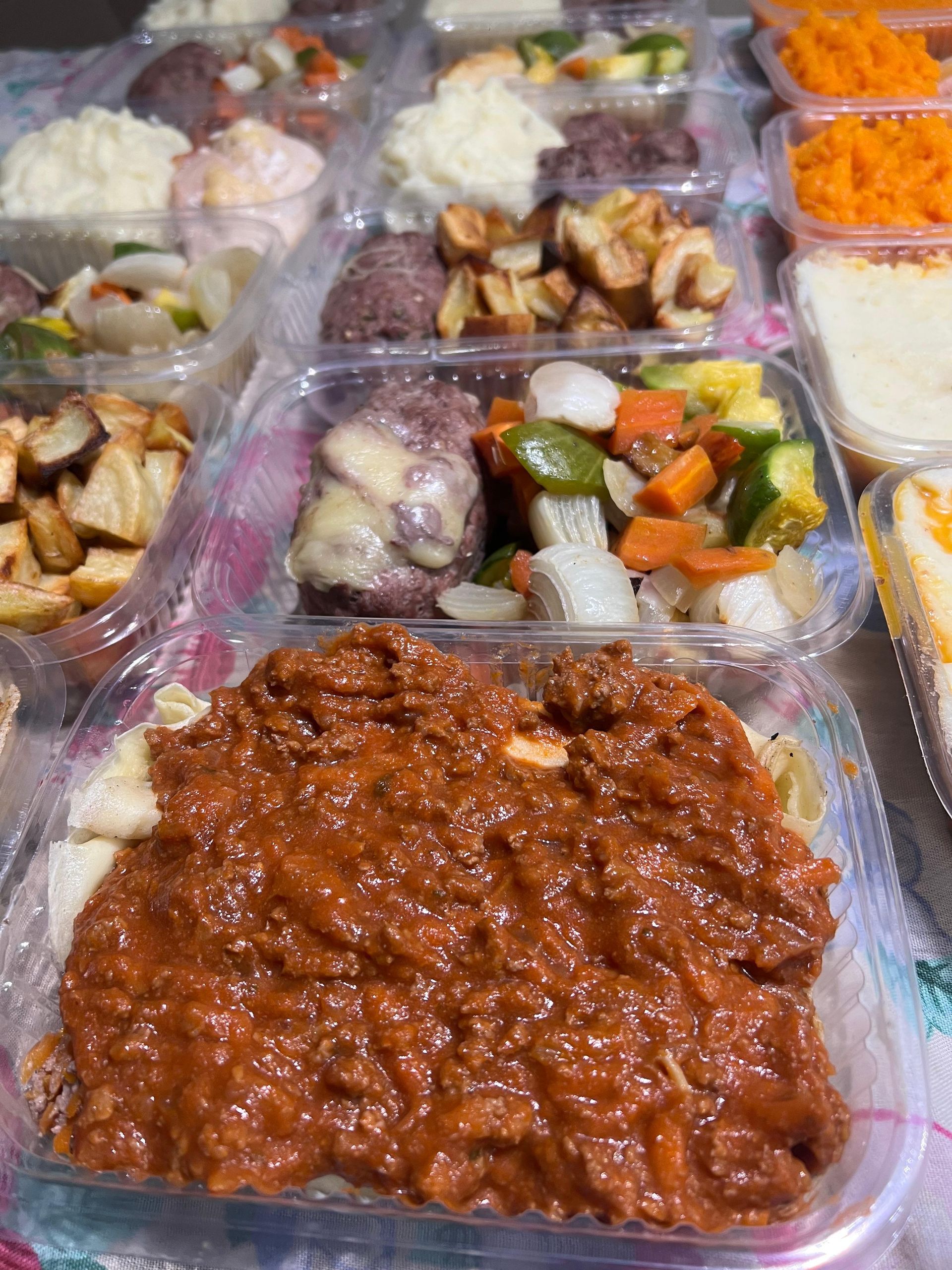 Un montón de recipientes de plástico llenos de comida están sobre una mesa.